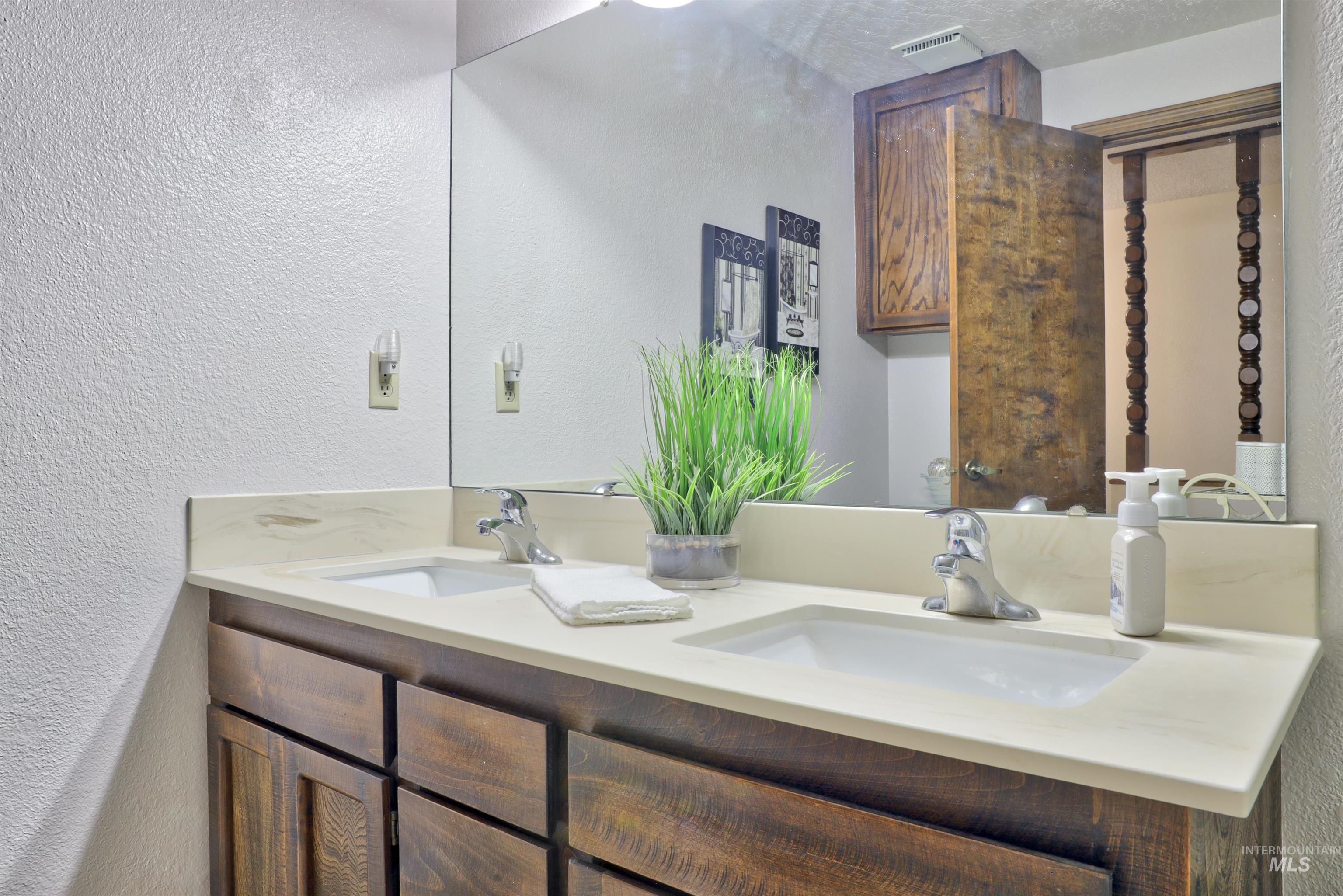 Full bath with a textured wall and double vanity