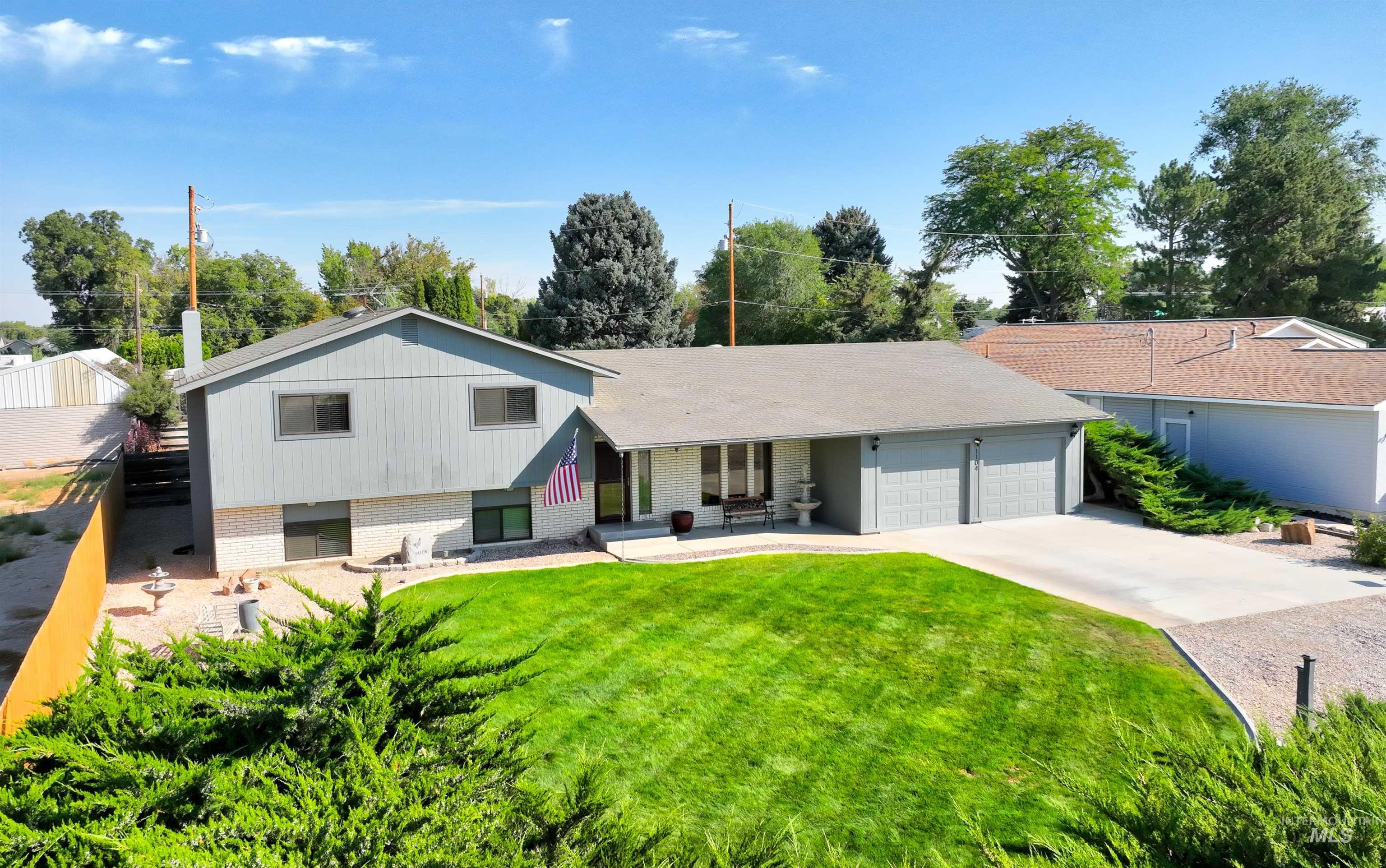 Split level home with brick siding, a garage, driveway, and a front yard