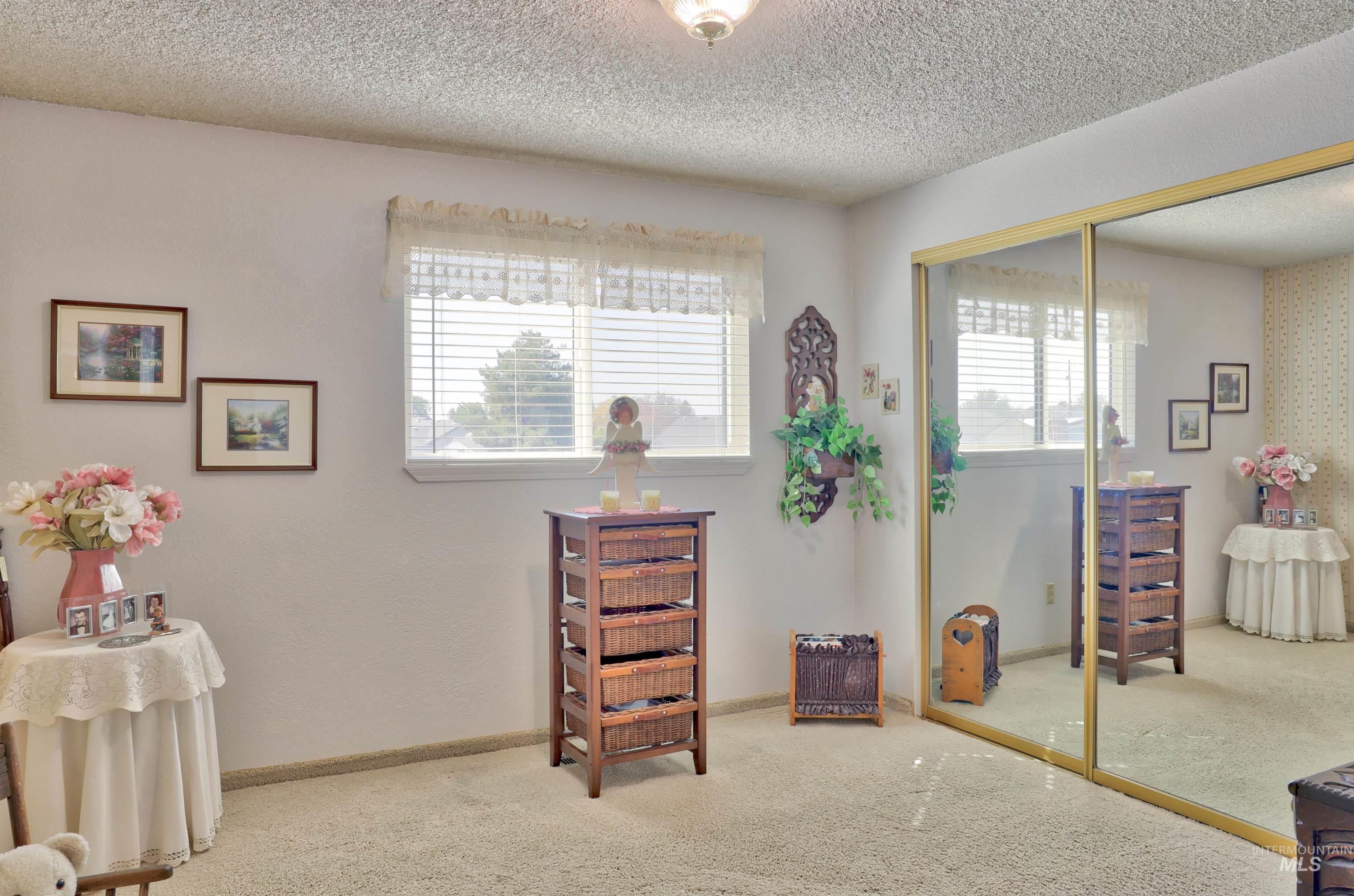 Bedroom with carpet flooring, multiple windows, a closet, and a textured ceiling