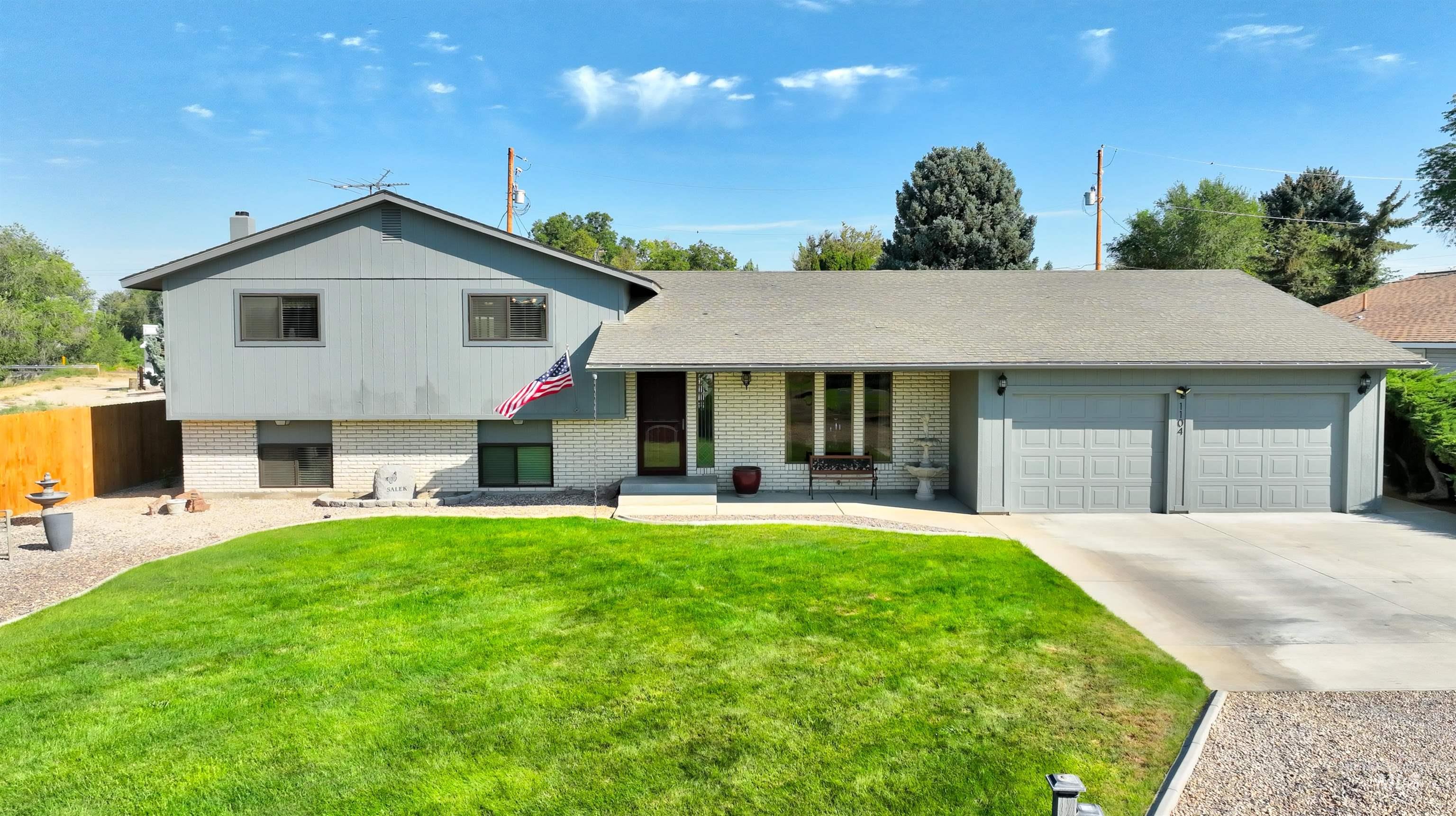 Tri-level home with brick siding, driveway, a garage, and roof with shingles