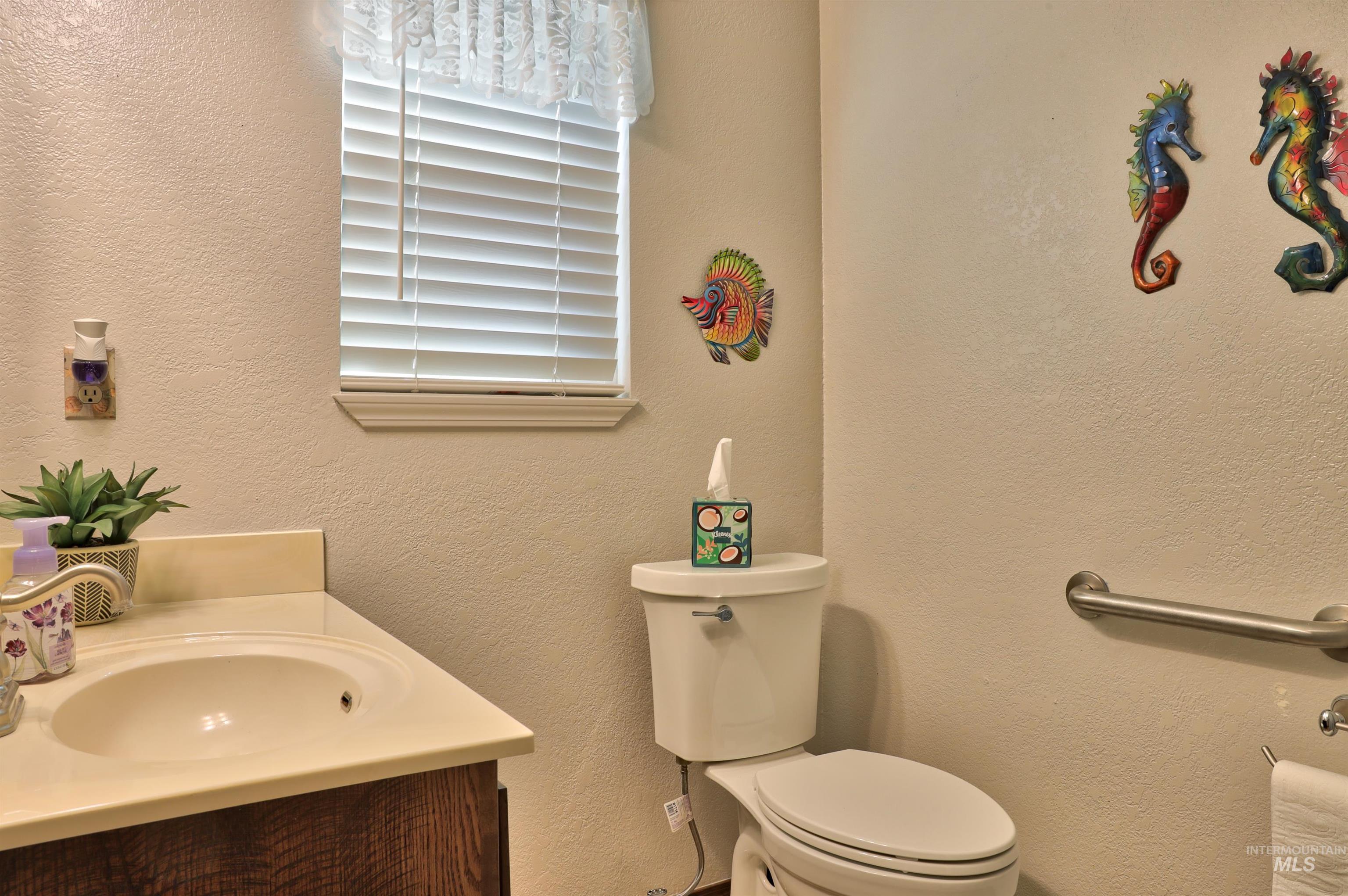 Half bathroom featuring a textured wall and vanity