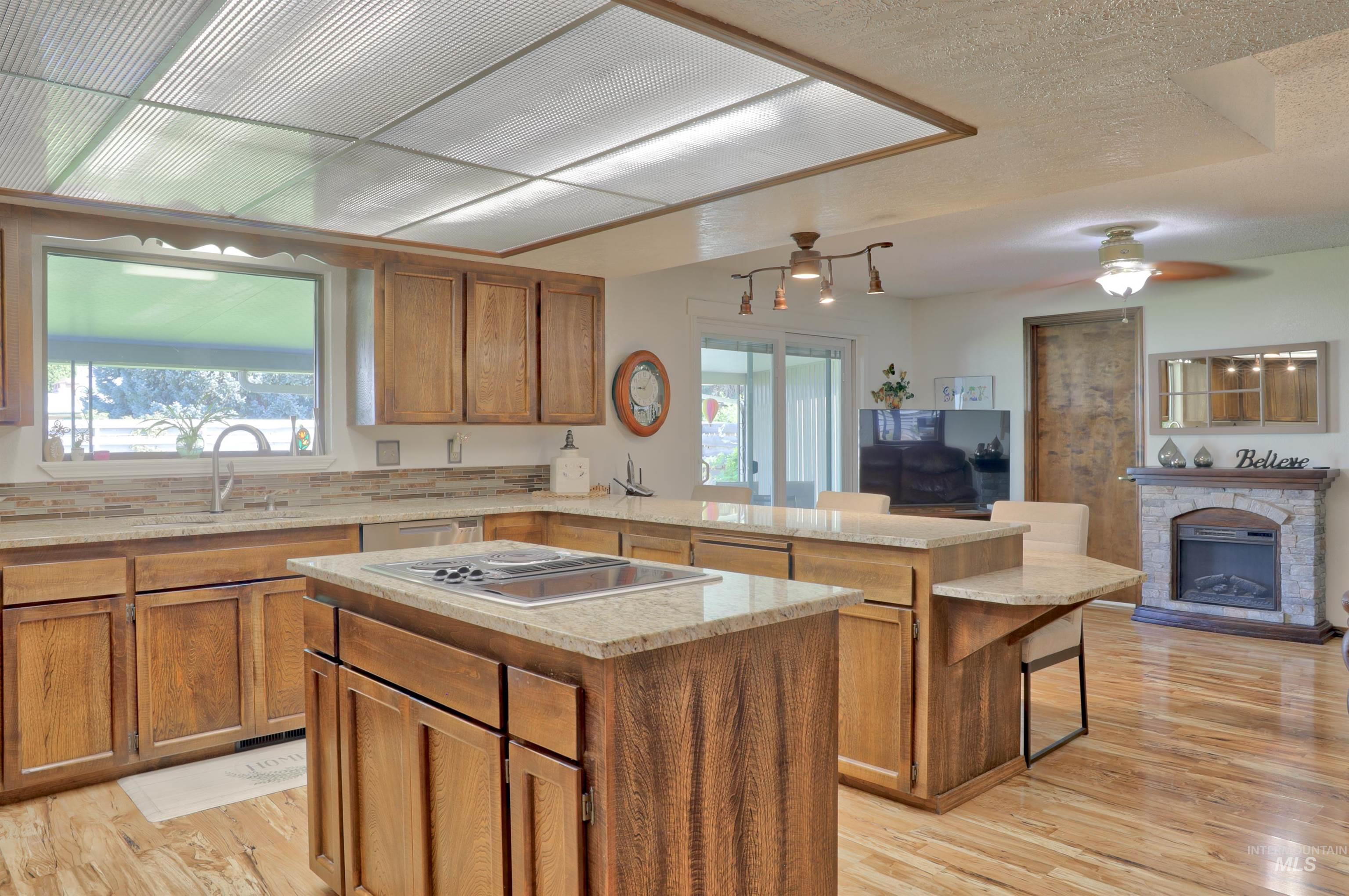Kitchen featuring brown cabinetry, a kitchen island, open floor plan, light wood-type flooring, and a textured ceiling