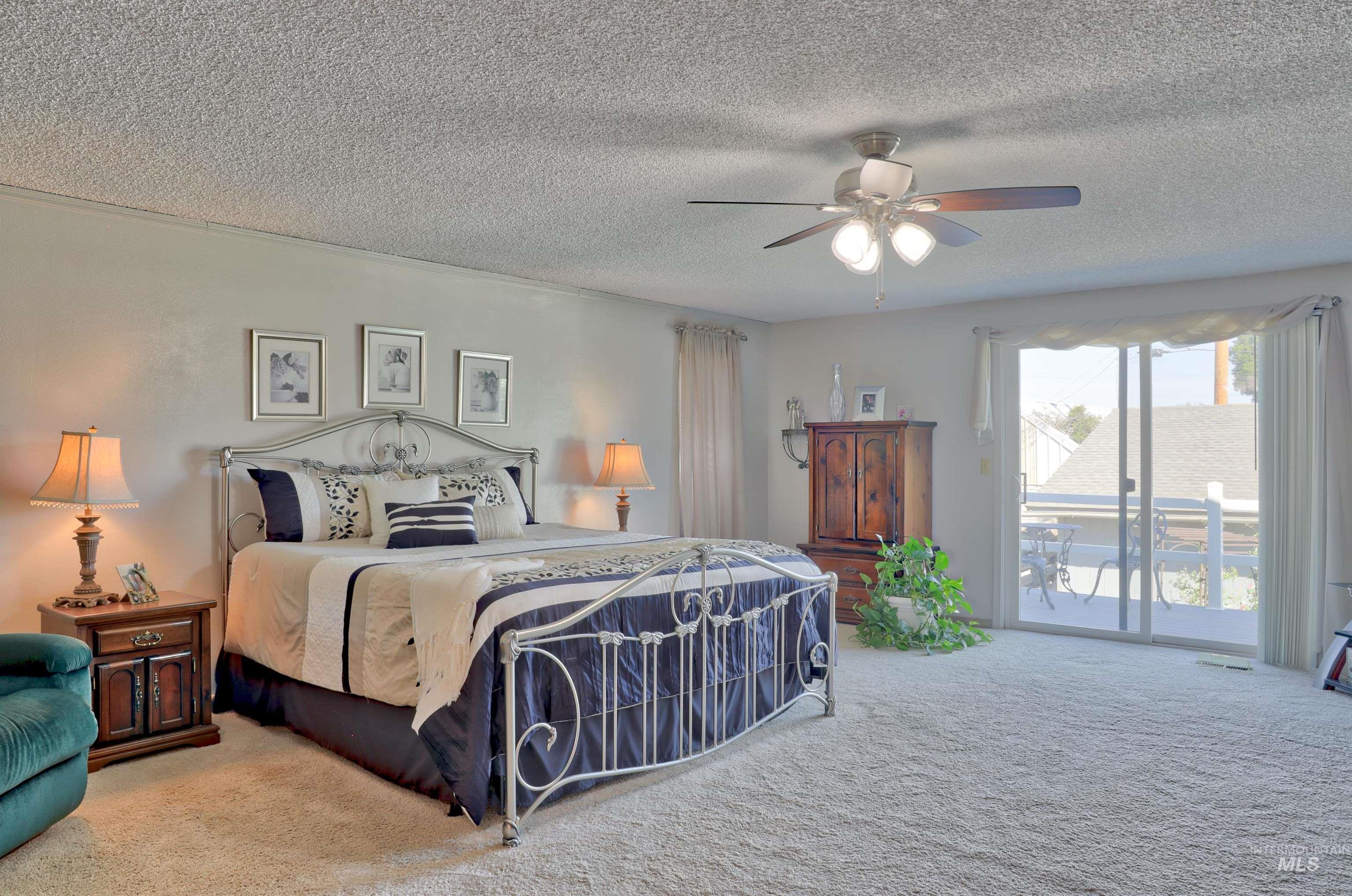 Carpeted bedroom featuring access to outside, ceiling fan, and a textured ceiling