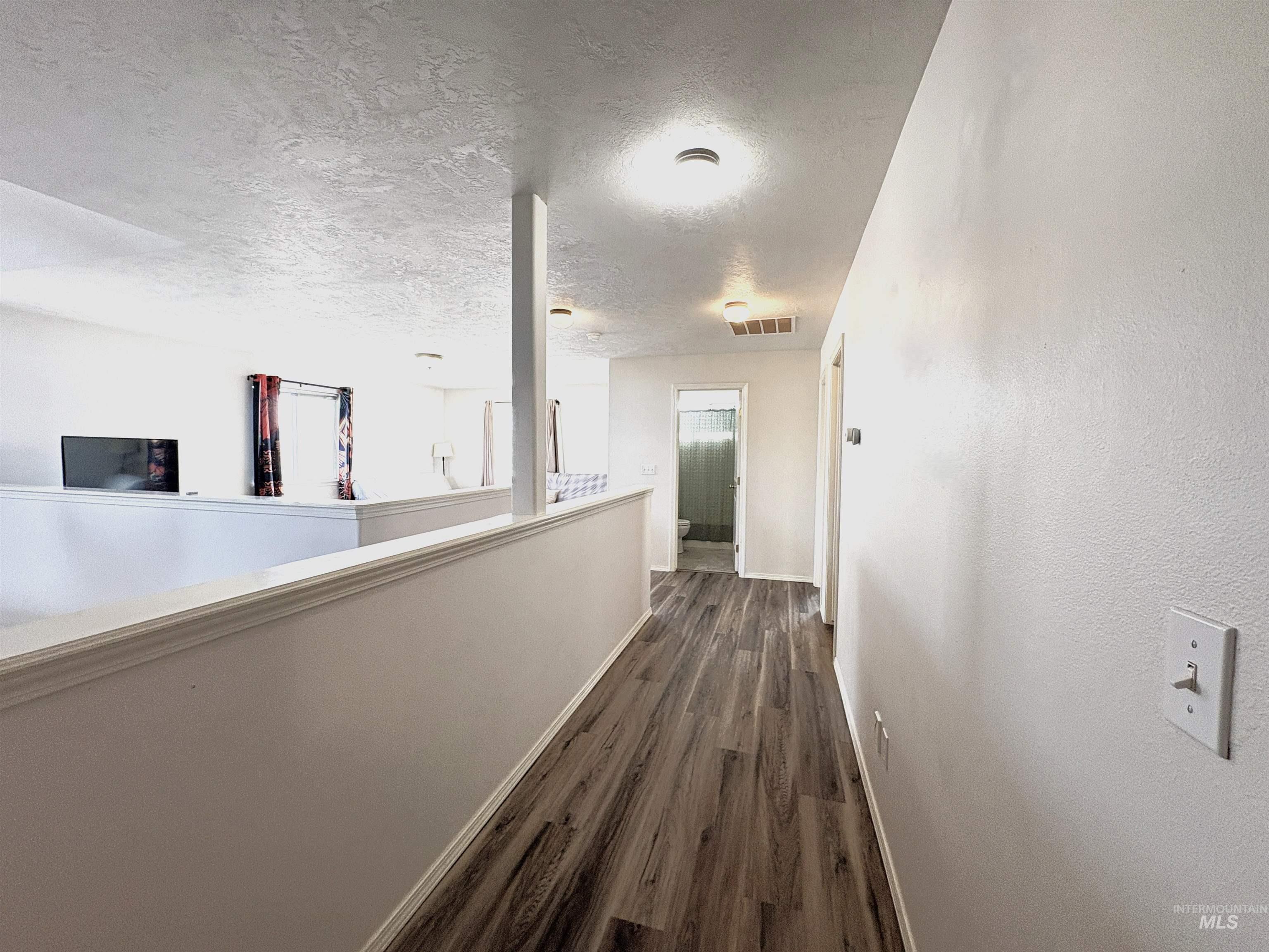 Hall with a textured ceiling and dark wood finished floors