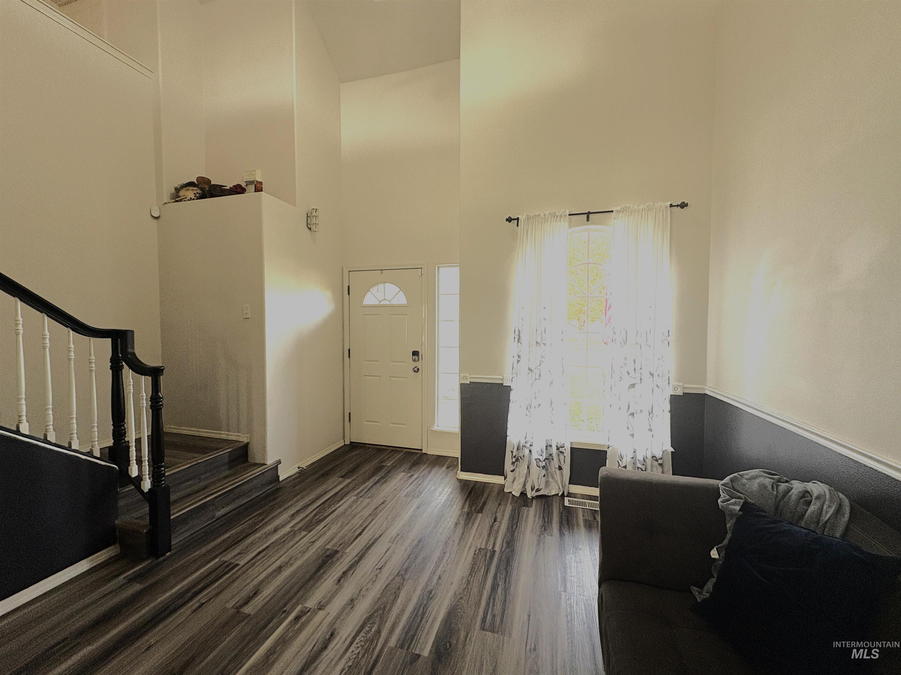 Entrance foyer featuring a towering ceiling, dark wood-style flooring, and stairs