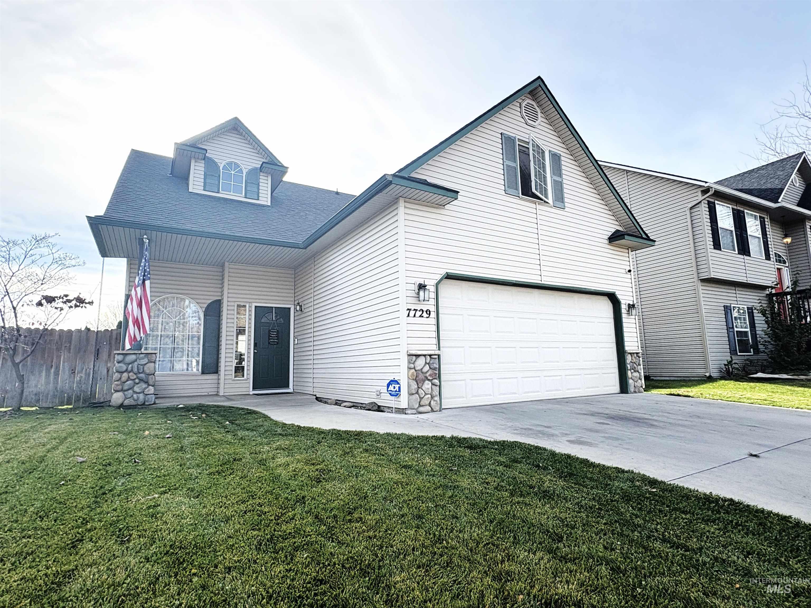 Traditional-style home with a shingled roof, stone siding, driveway, an attached garage, and covered porch