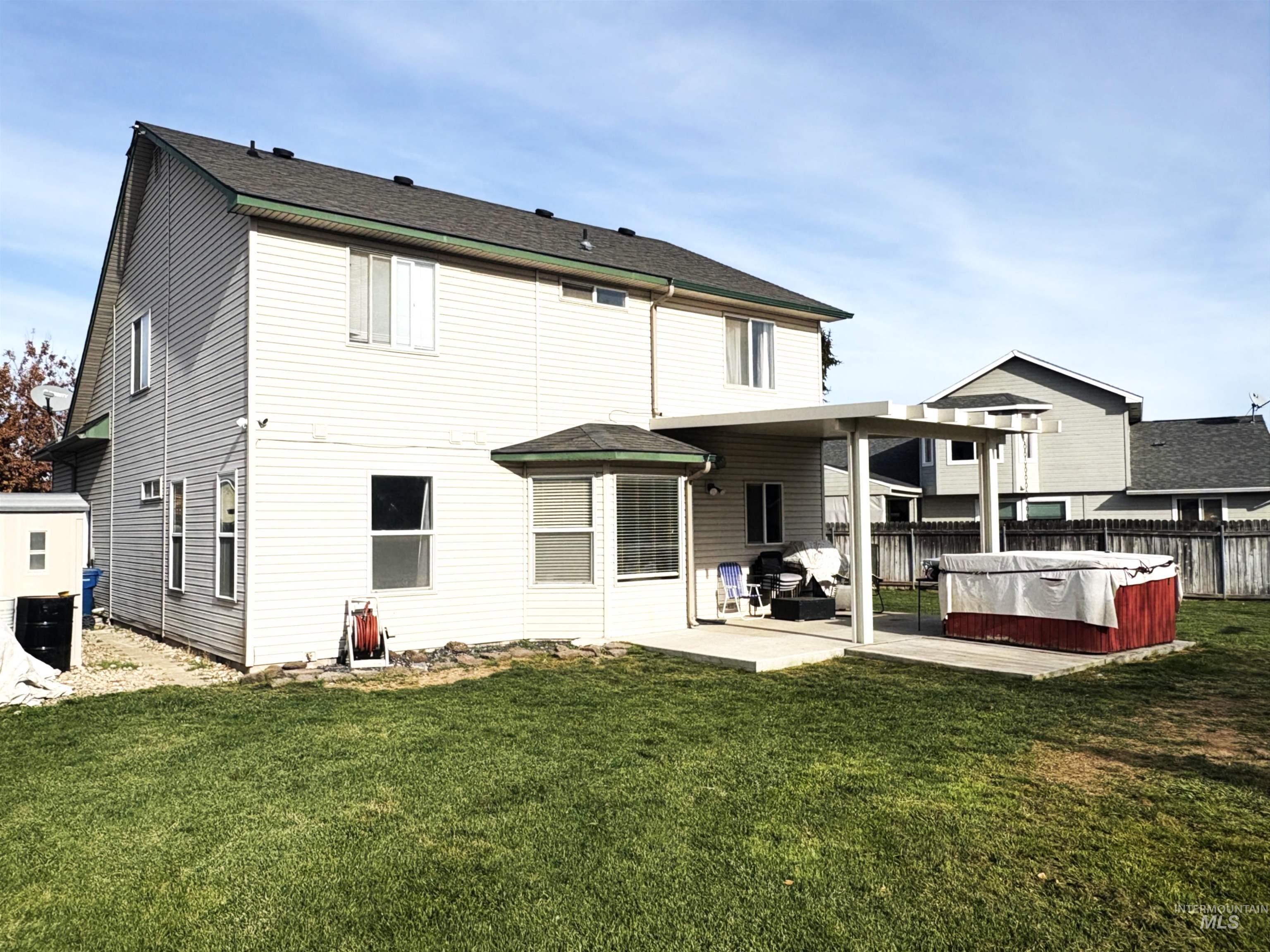 Back of house with a patio area and a hot tub
