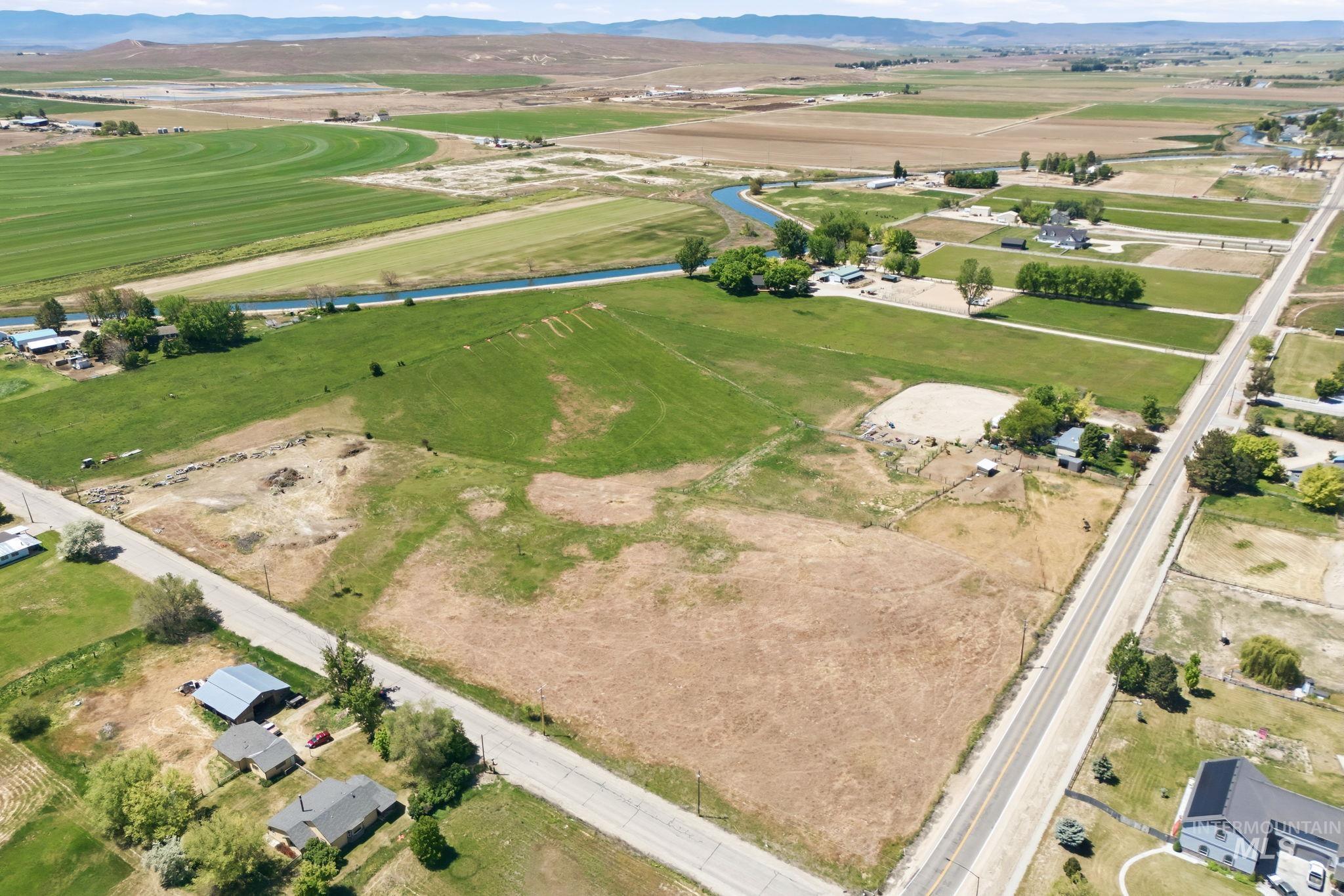 Expansive land parcel with direct road frontage, featuring a mix of cultivated fields and undeveloped terrain
