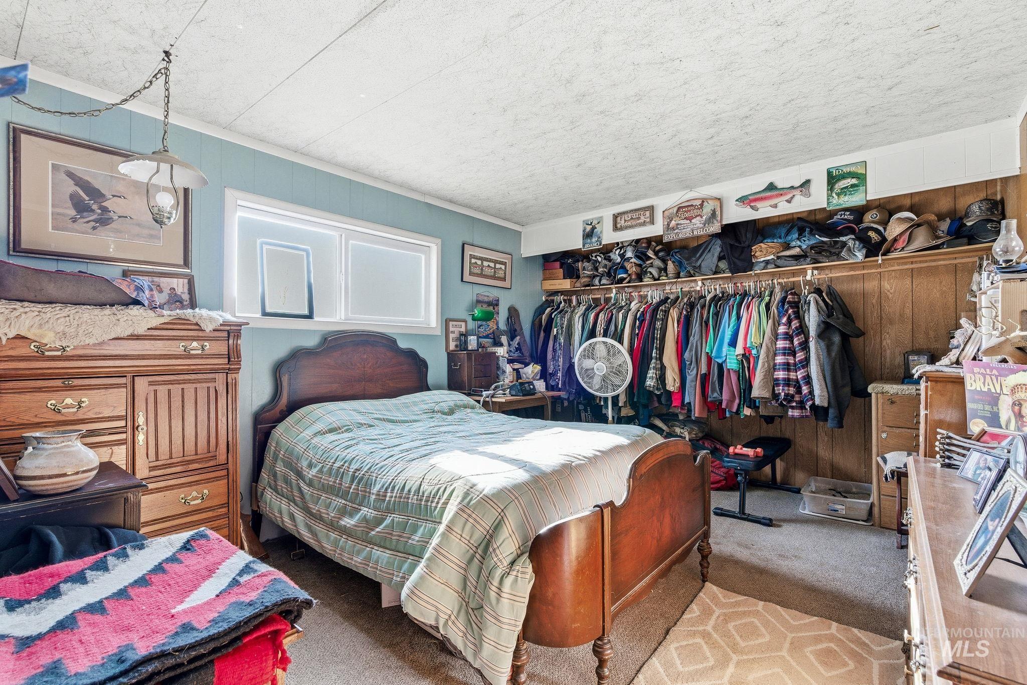Carpeted bedroom with wood walls, a closet, and ornamental molding