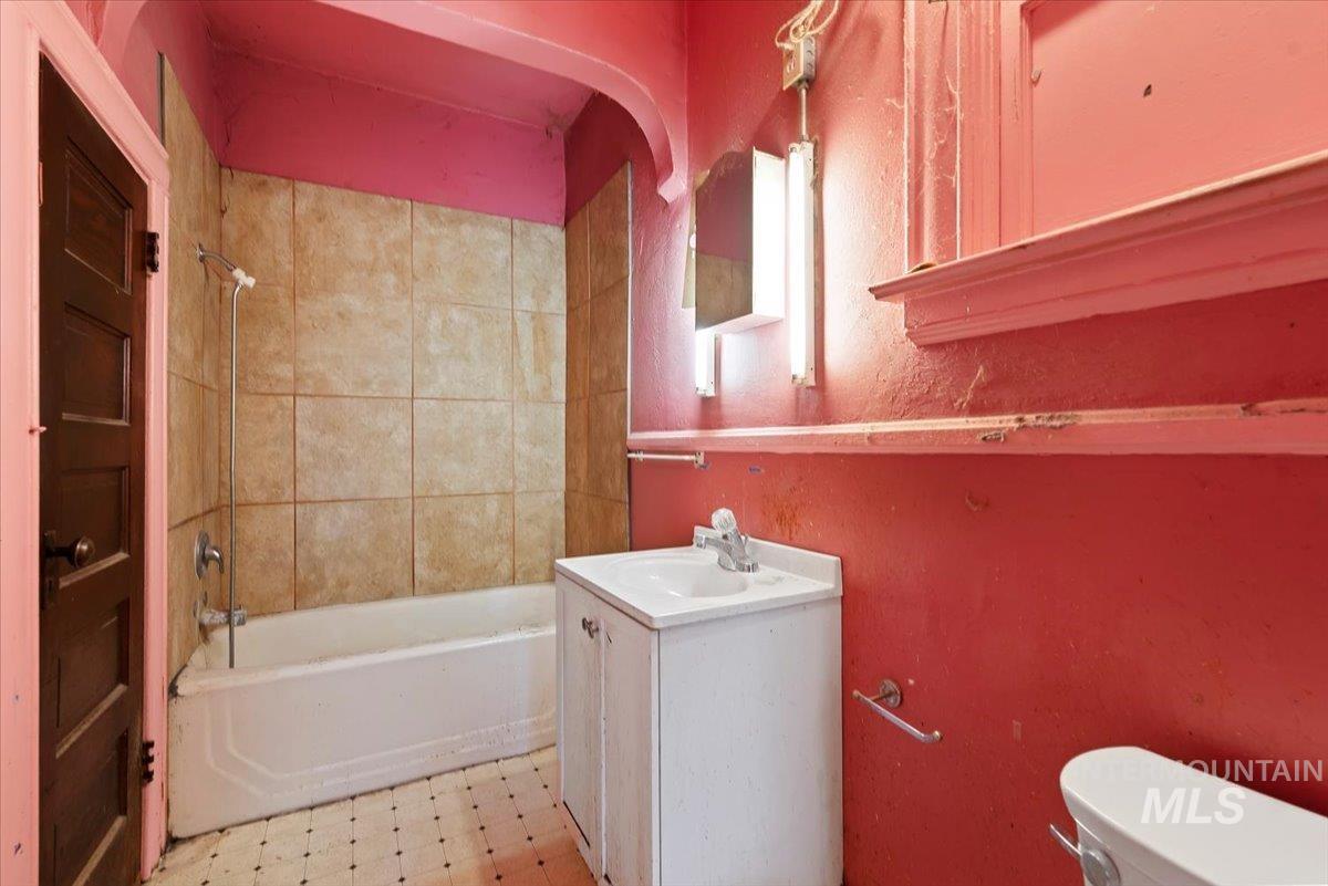 Bathroom featuring light flooring, vanity, and bathing tub / shower combination