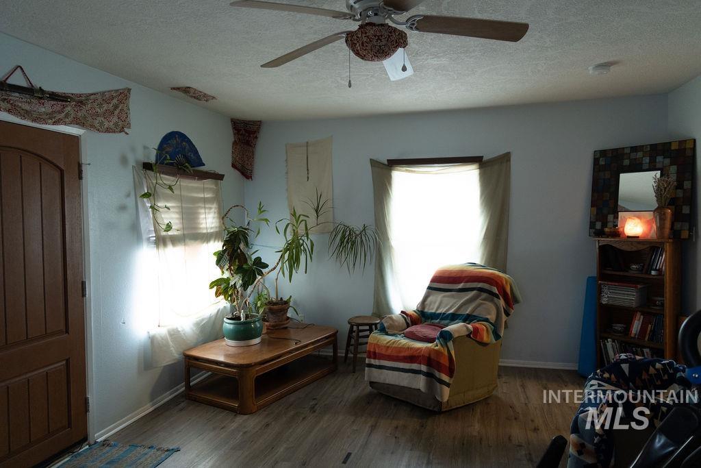 Sitting room featuring a textured ceiling, wood finished floors, and ceiling fan