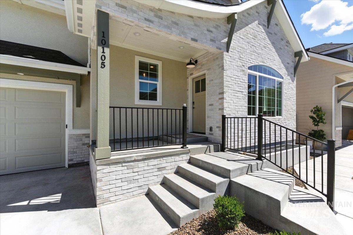 Property entrance featuring a porch, stone siding, driveway, and stucco siding