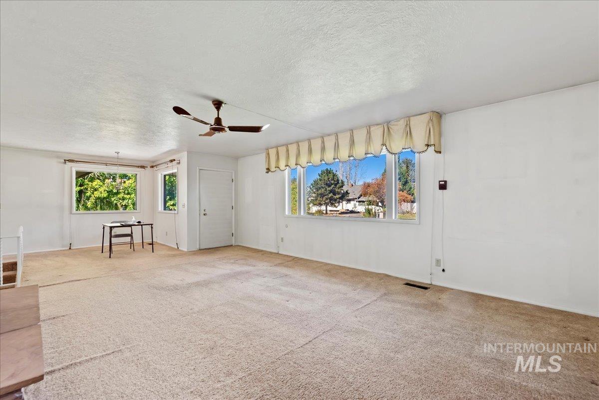 Unfurnished living room featuring a textured ceiling, plenty of natural light, carpet flooring, and ceiling fan
