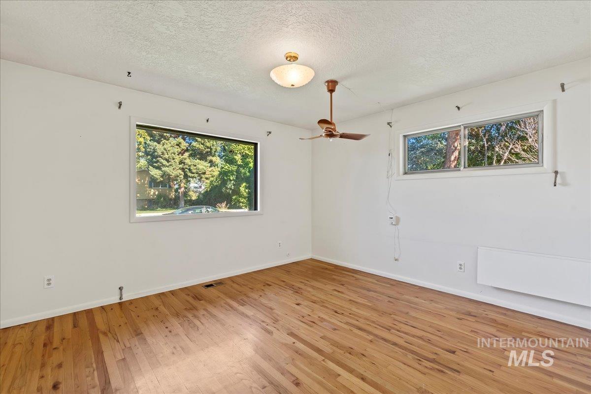 Unfurnished room with a textured ceiling, hardwood / wood-style flooring, and ceiling fan