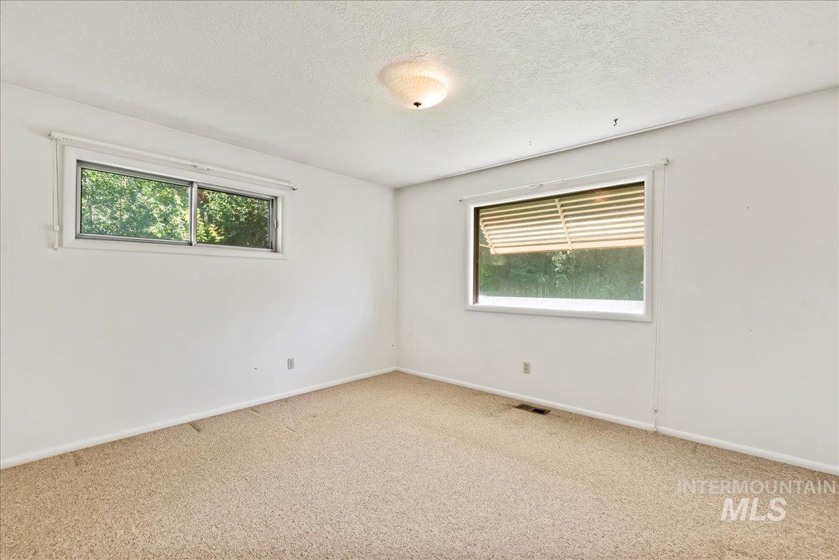 Carpeted spare room with plenty of natural light and a textured ceiling