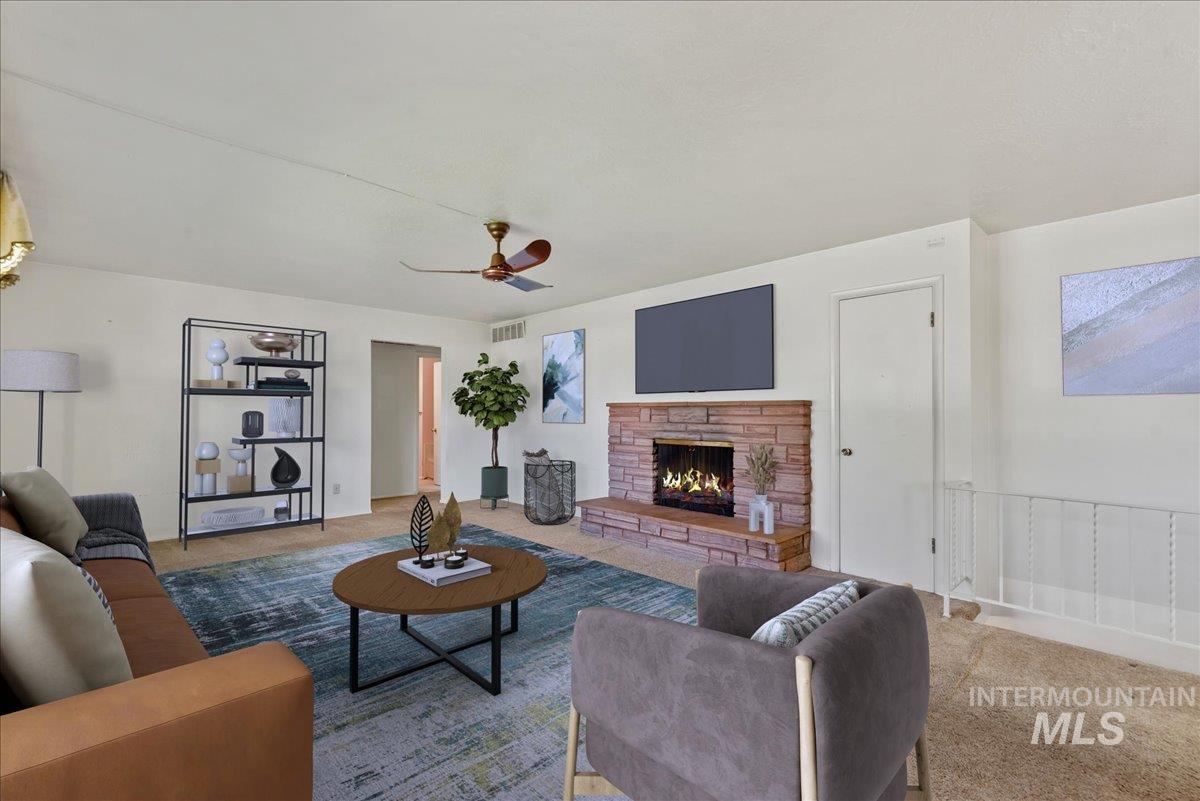 Carpeted living room featuring a fireplace and a ceiling fan