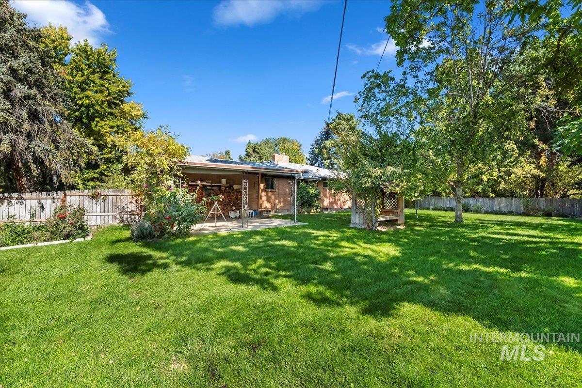 Rear view of house with a fenced backyard, a patio area, solar panels, and a chimney