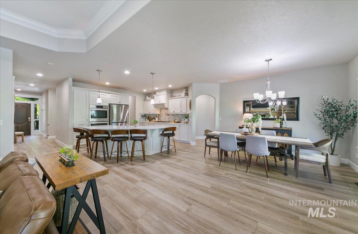 Dining space featuring arched walkways, light wood-style floors, recessed lighting, a chandelier, and ornamental molding