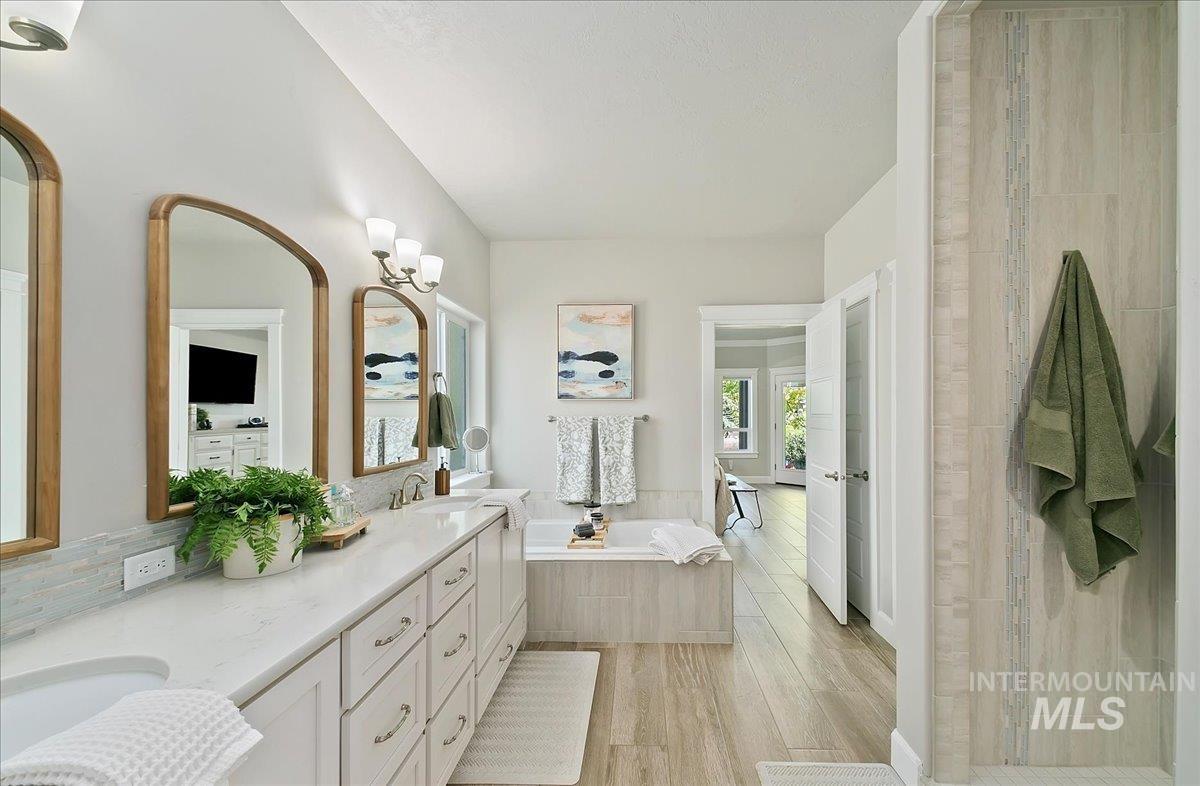 Bathroom with double vanity, a garden tub, and wood finished floors
