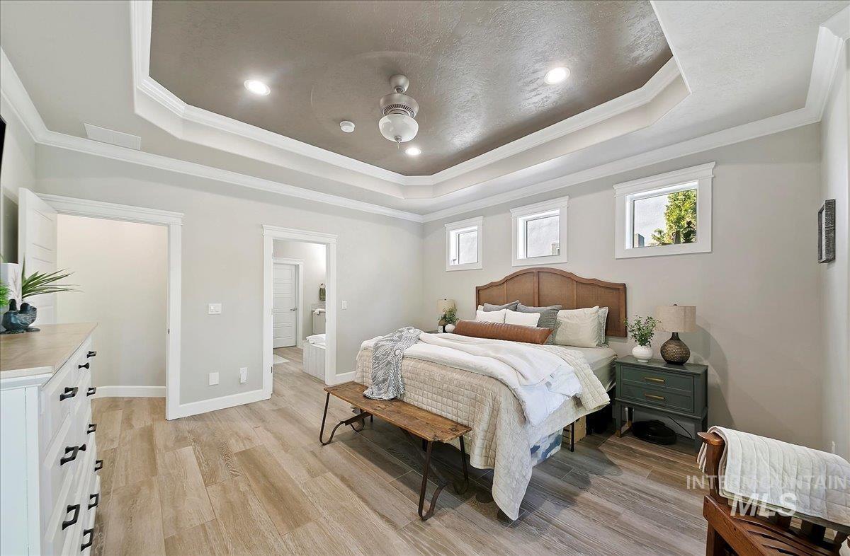Bedroom with crown molding, light wood finished floors, a tray ceiling, and recessed lighting