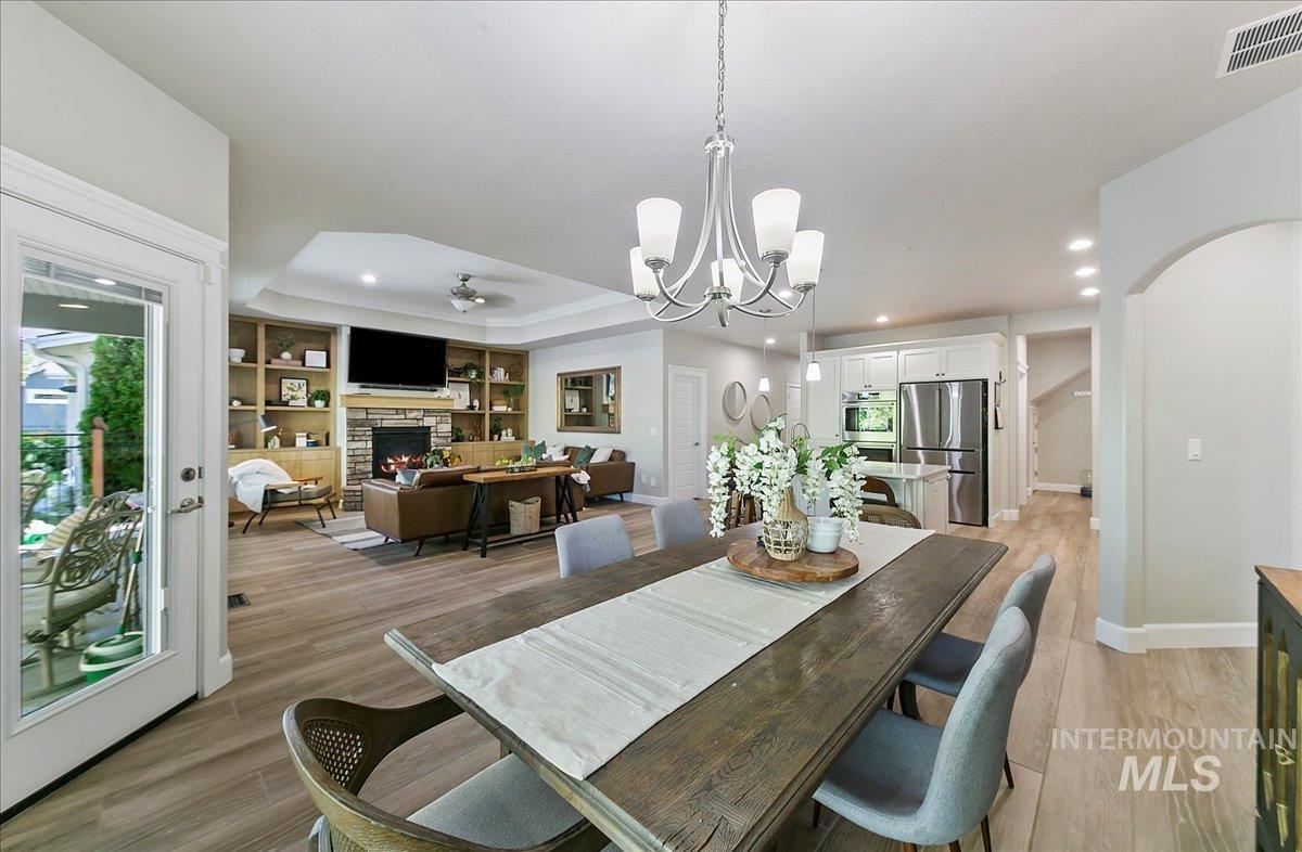 Dining space with a fireplace, arched walkways, light wood-style flooring, built in shelves, and recessed lighting