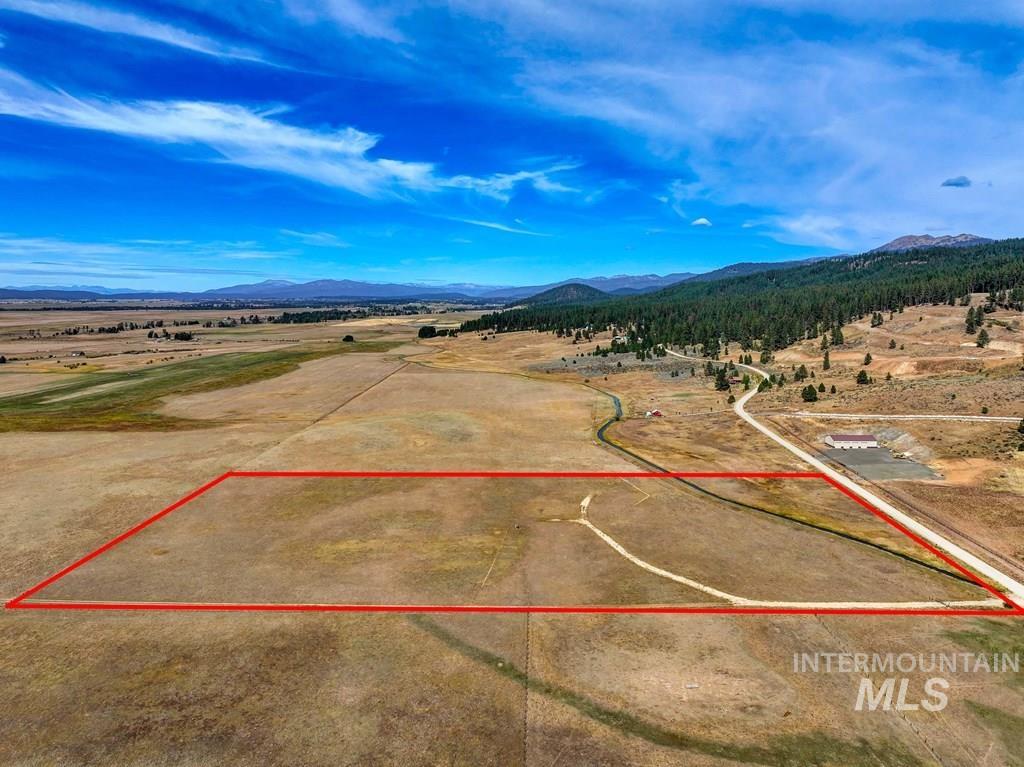 Aerial overview of property's location with a mountainous background and property boundaries highlighted