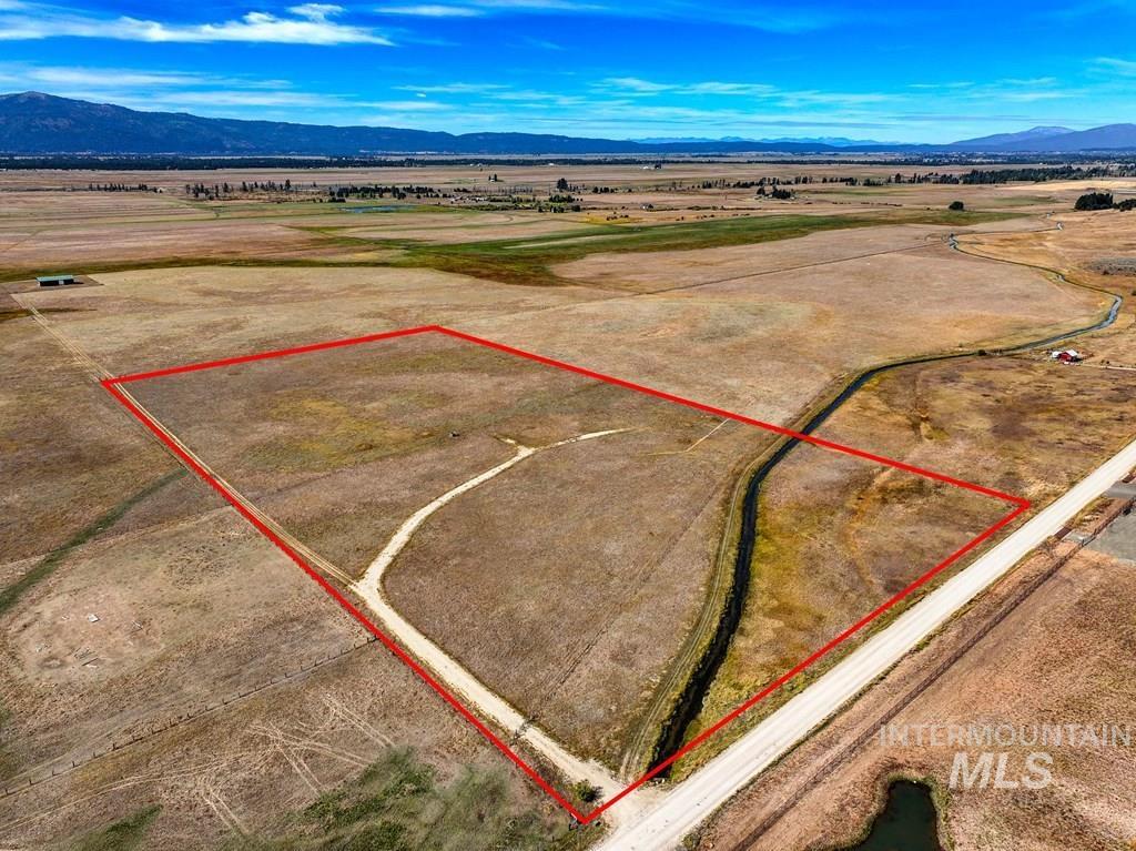 Aerial view of sparsely populated area featuring property parcel outlined and a mountainous background