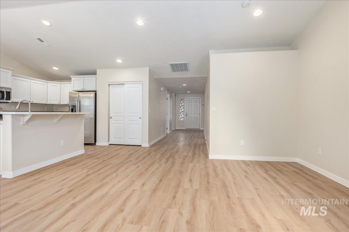 Kitchen with a kitchen breakfast bar, recessed lighting, light wood finished floors, white cabinets, and appliances with stainless steel finishes