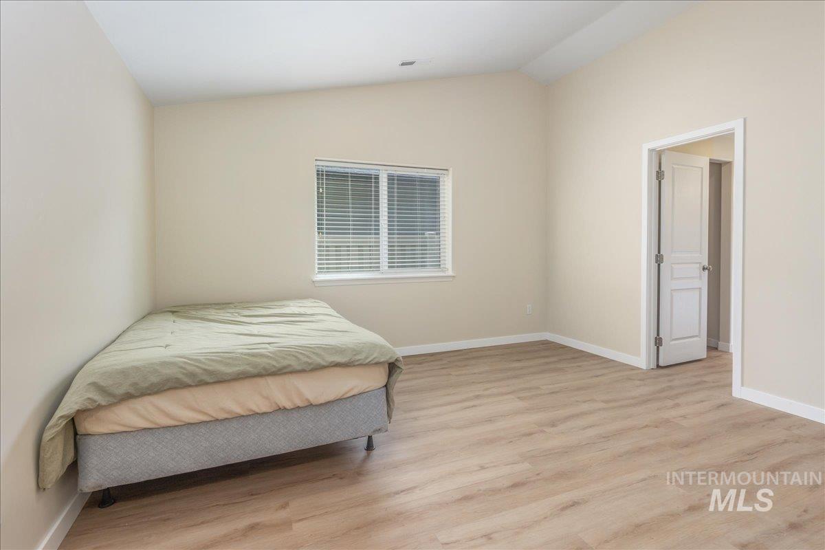 Bedroom with vaulted ceiling and light wood-style flooring