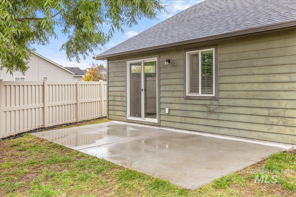 Back of house with a patio area and roof with shingles