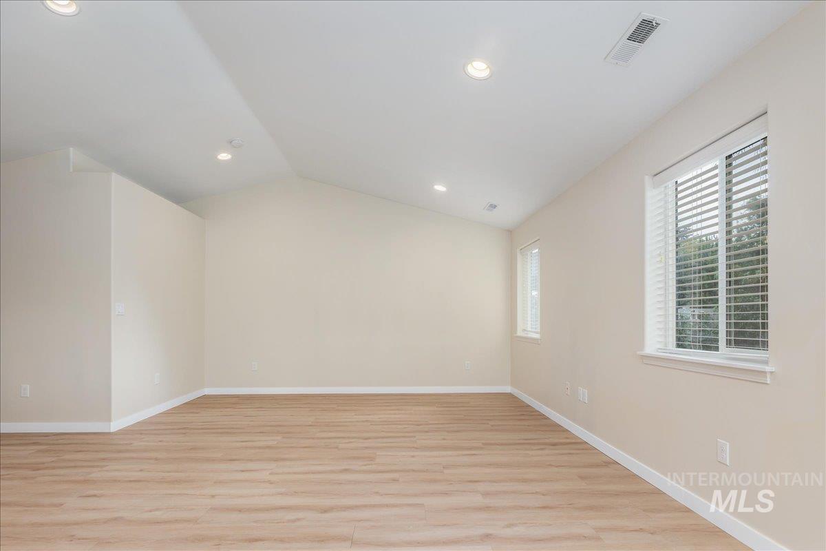 Unfurnished room with lofted ceiling, light wood-style floors, and recessed lighting