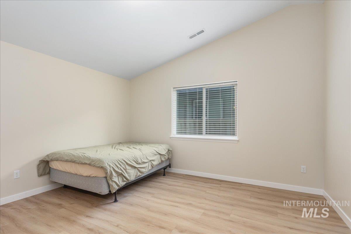 Bedroom with vaulted ceiling and light wood-style flooring