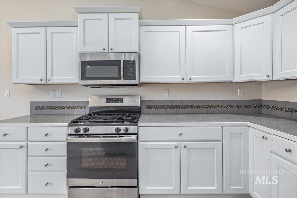 Kitchen featuring appliances with stainless steel finishes, white cabinetry, and light countertops