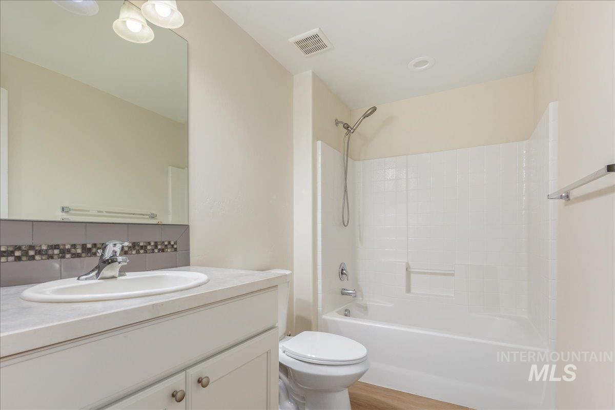 Bathroom with  shower combination, vanity, backsplash, and light wood-style flooring