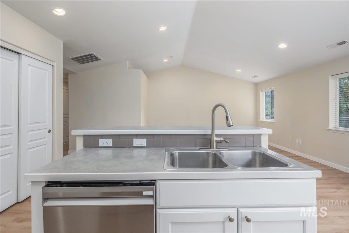 Kitchen featuring light wood-style floors, white cabinetry, recessed lighting, dishwasher, and light countertops