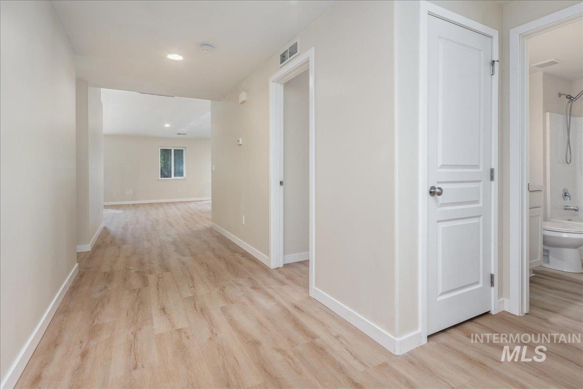 Hallway with light wood-style floors and recessed lighting
