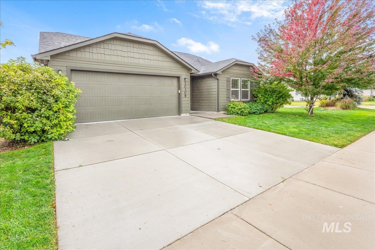 Ranch-style house featuring a front yard, concrete driveway, a garage, and roof with shingles