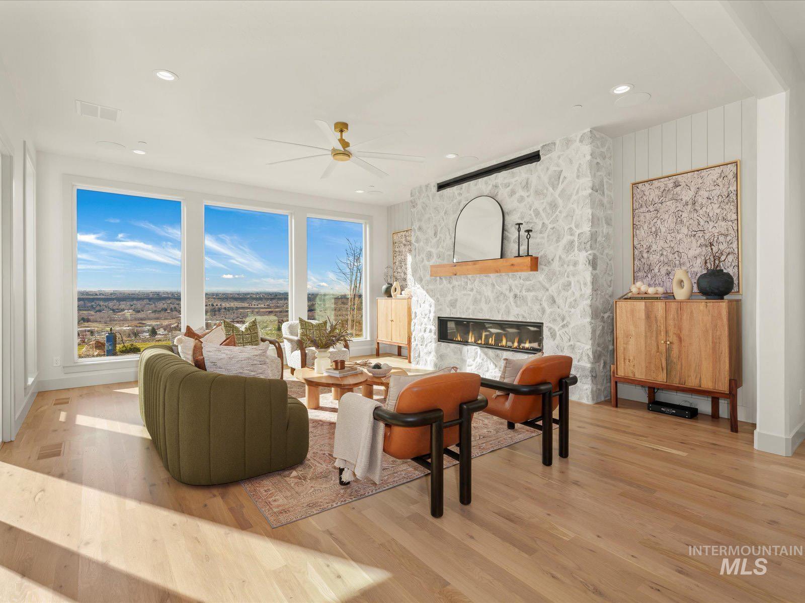 Living room featuring light wood finished floors, a ceiling fan, a fireplace, and recessed lighting