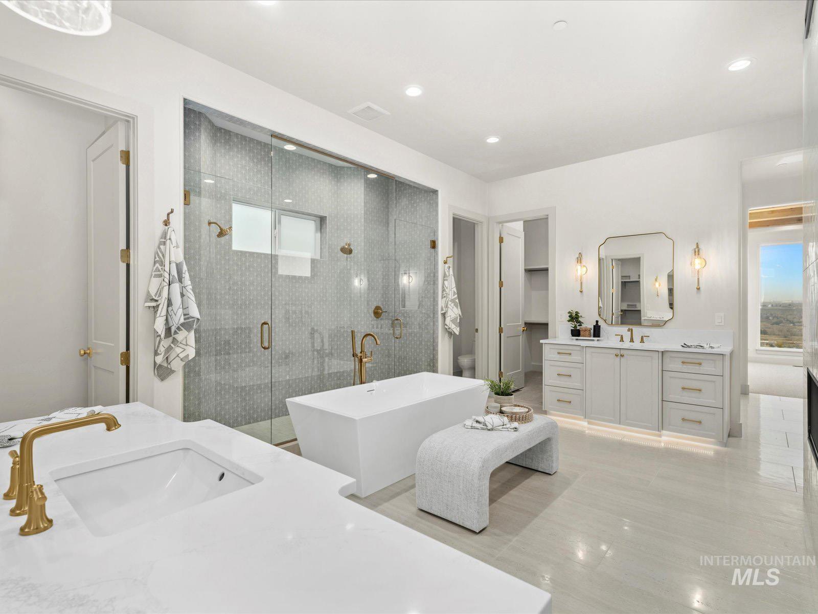Full bath featuring a soaking tub, two vanities, a shower stall, a spacious closet, and recessed lighting