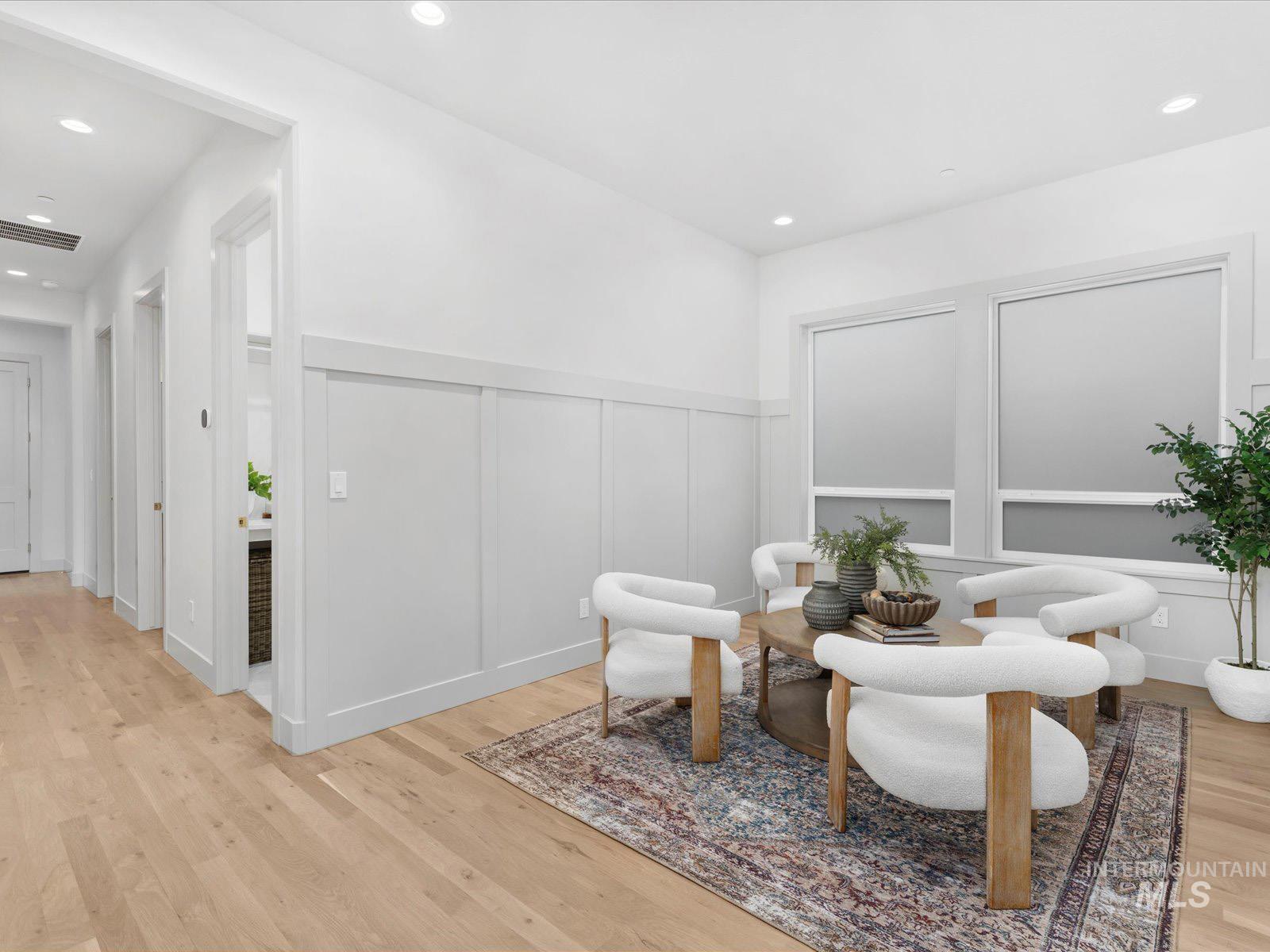 Living area featuring a decorative wall, wainscoting, light wood-style flooring, and recessed lighting