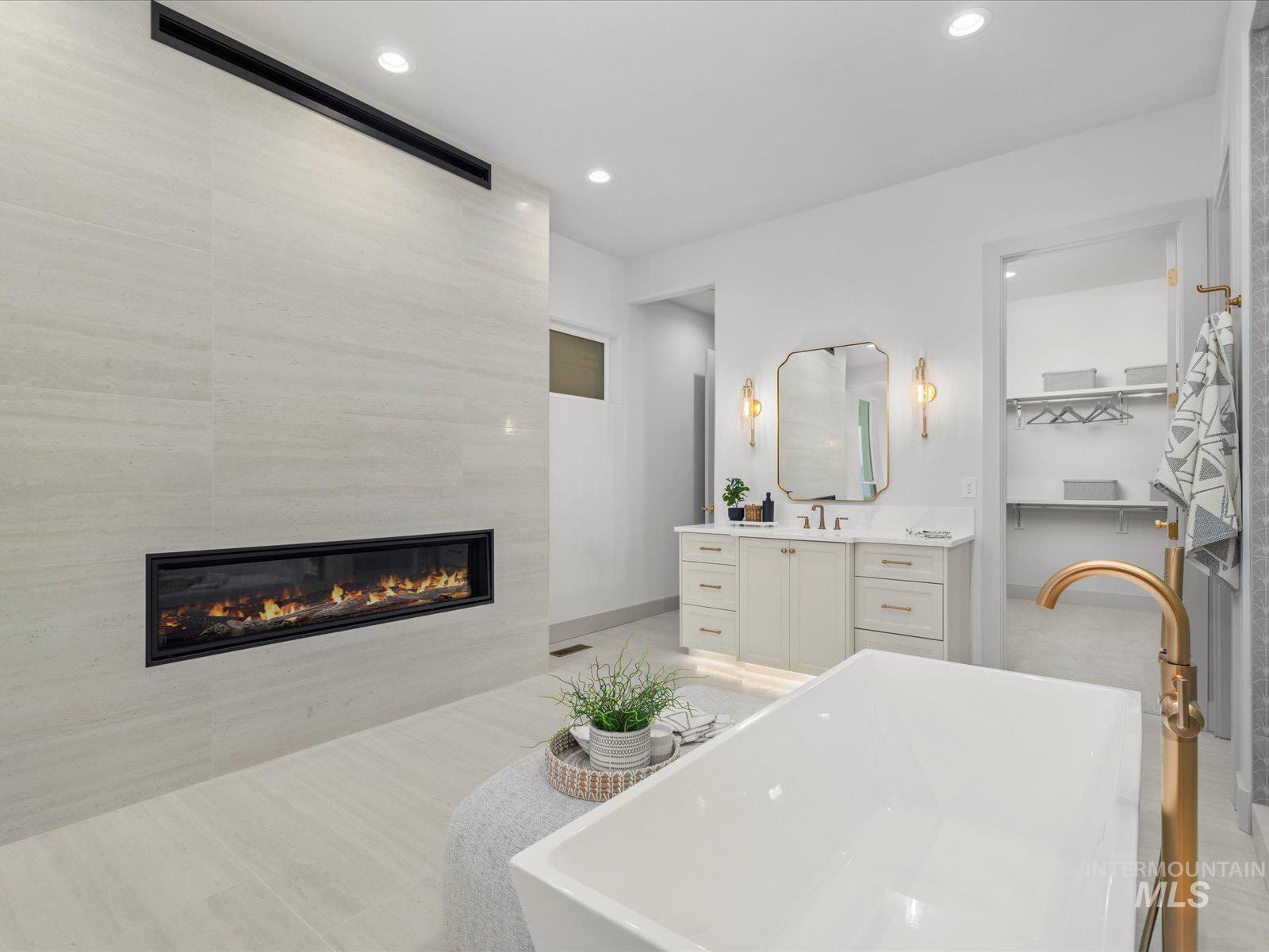 Bathroom featuring vanity, a freestanding bath, a fireplace, recessed lighting, and a walk in closet