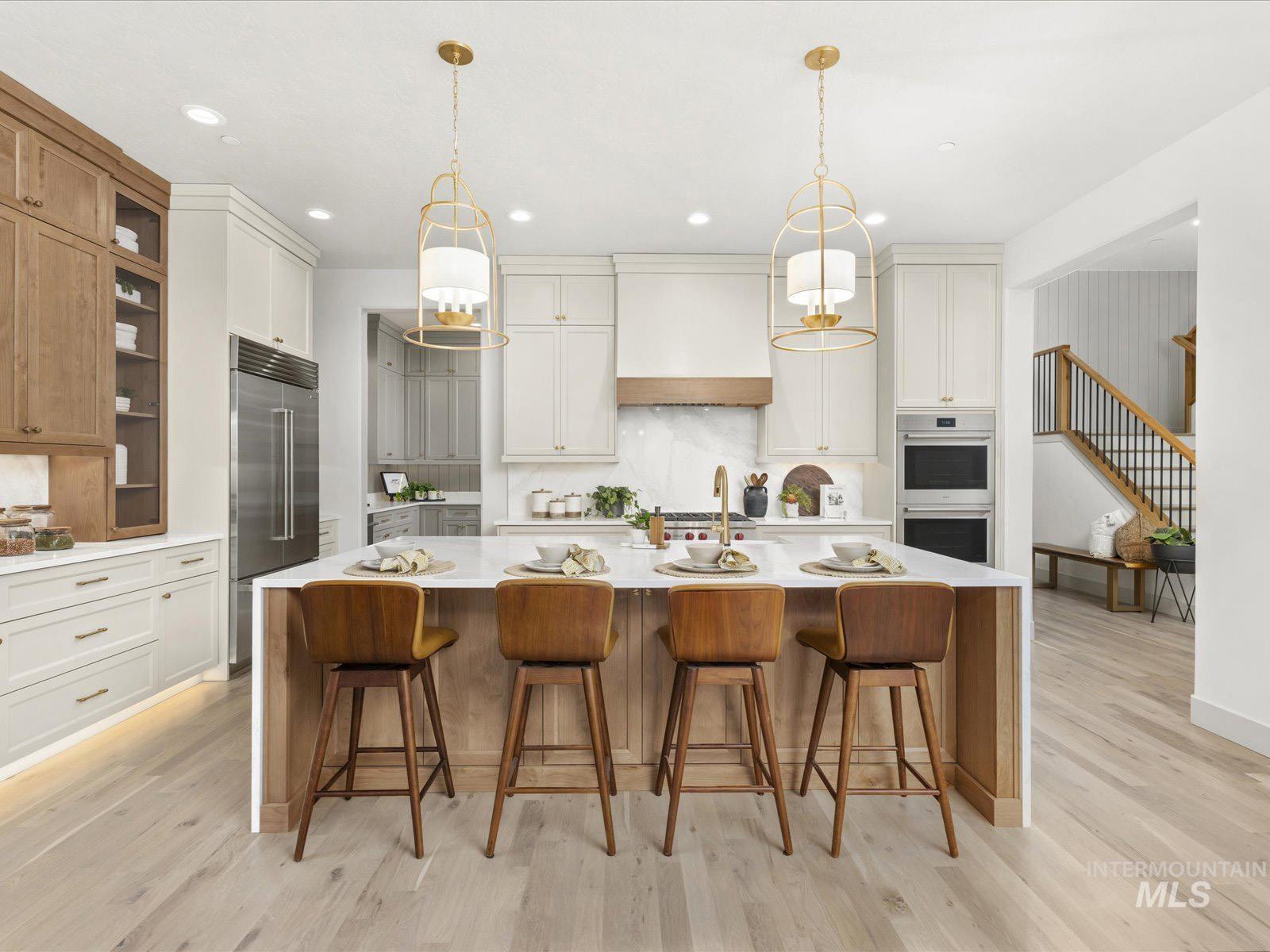 Kitchen with light stone counters, a large island, a breakfast bar, stainless steel appliances, and pendant lighting