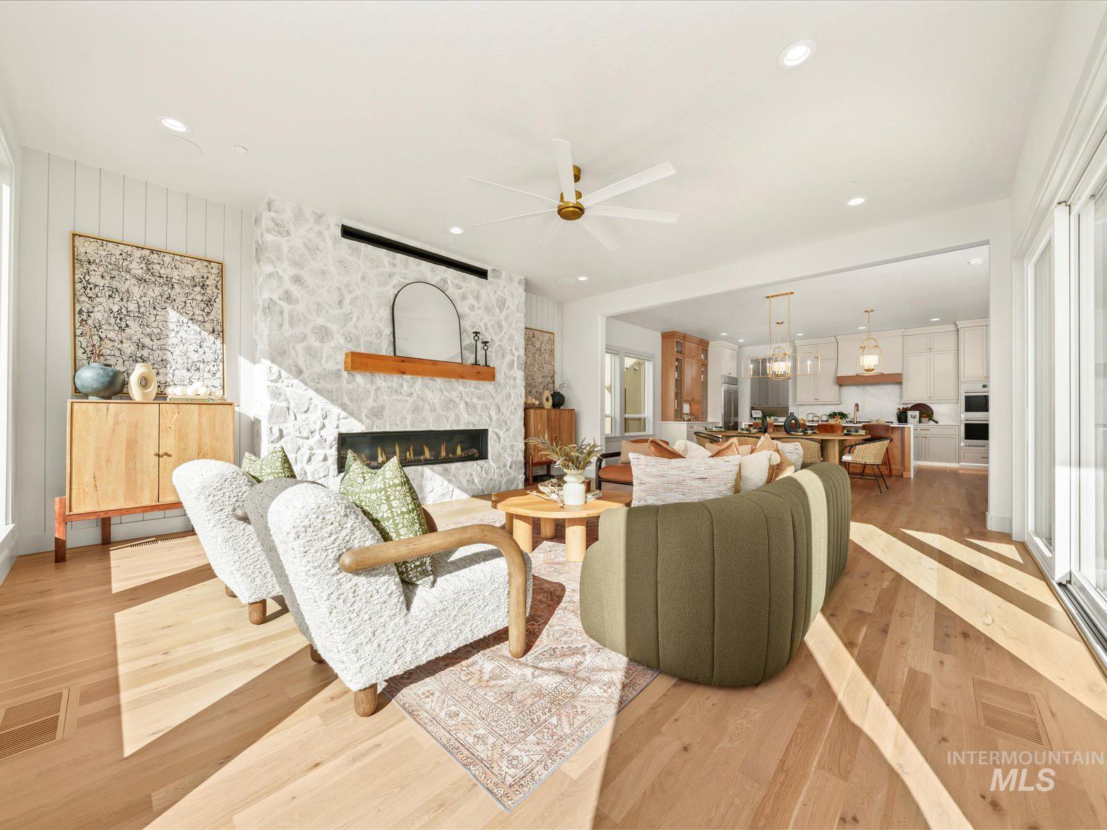 Living room with light wood-style flooring, a ceiling fan, a fireplace, and recessed lighting