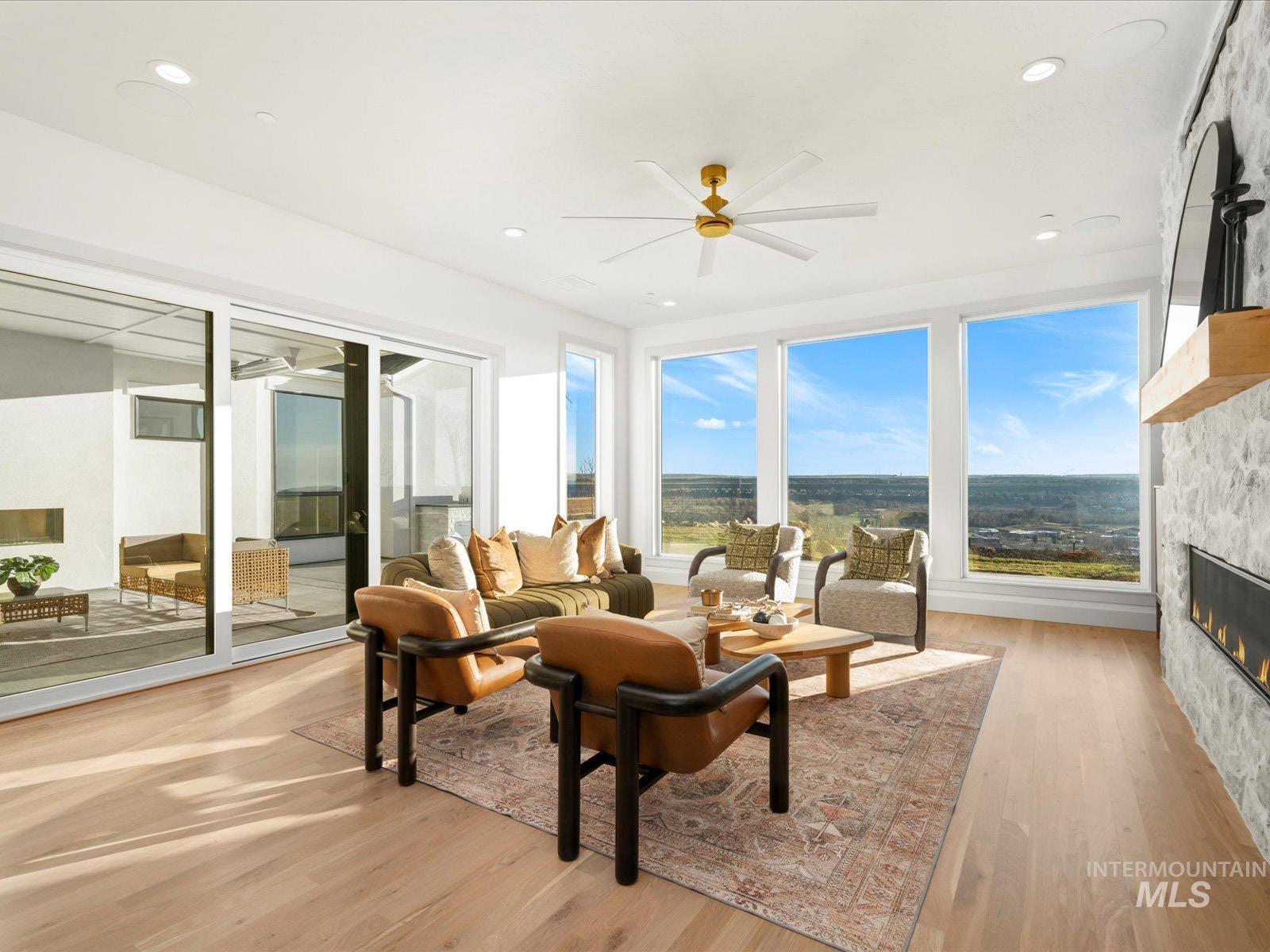 Living area featuring ceiling fan, light wood-style flooring, a glass covered fireplace, healthy amount of natural light, and recessed lighting