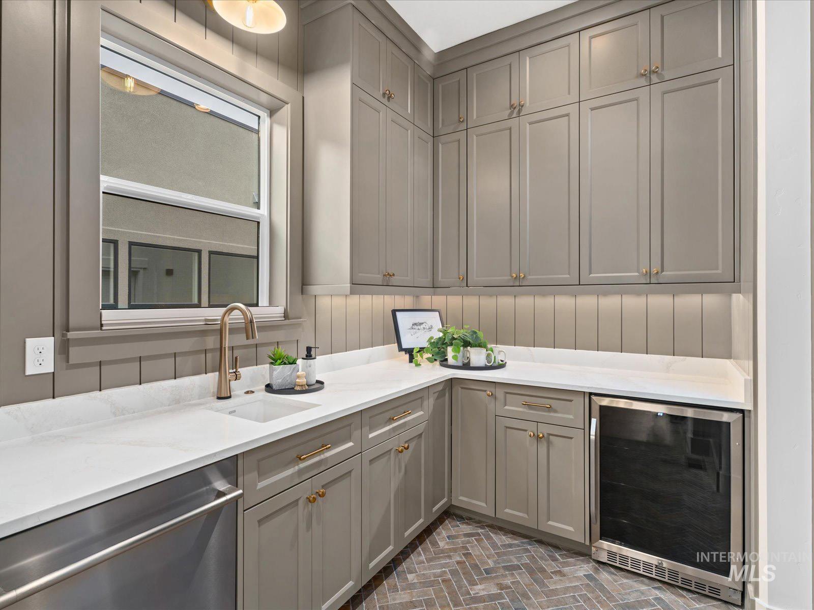 Bar area featuring gray cabinetry, wine cooler, stainless steel dishwasher, and brick floors