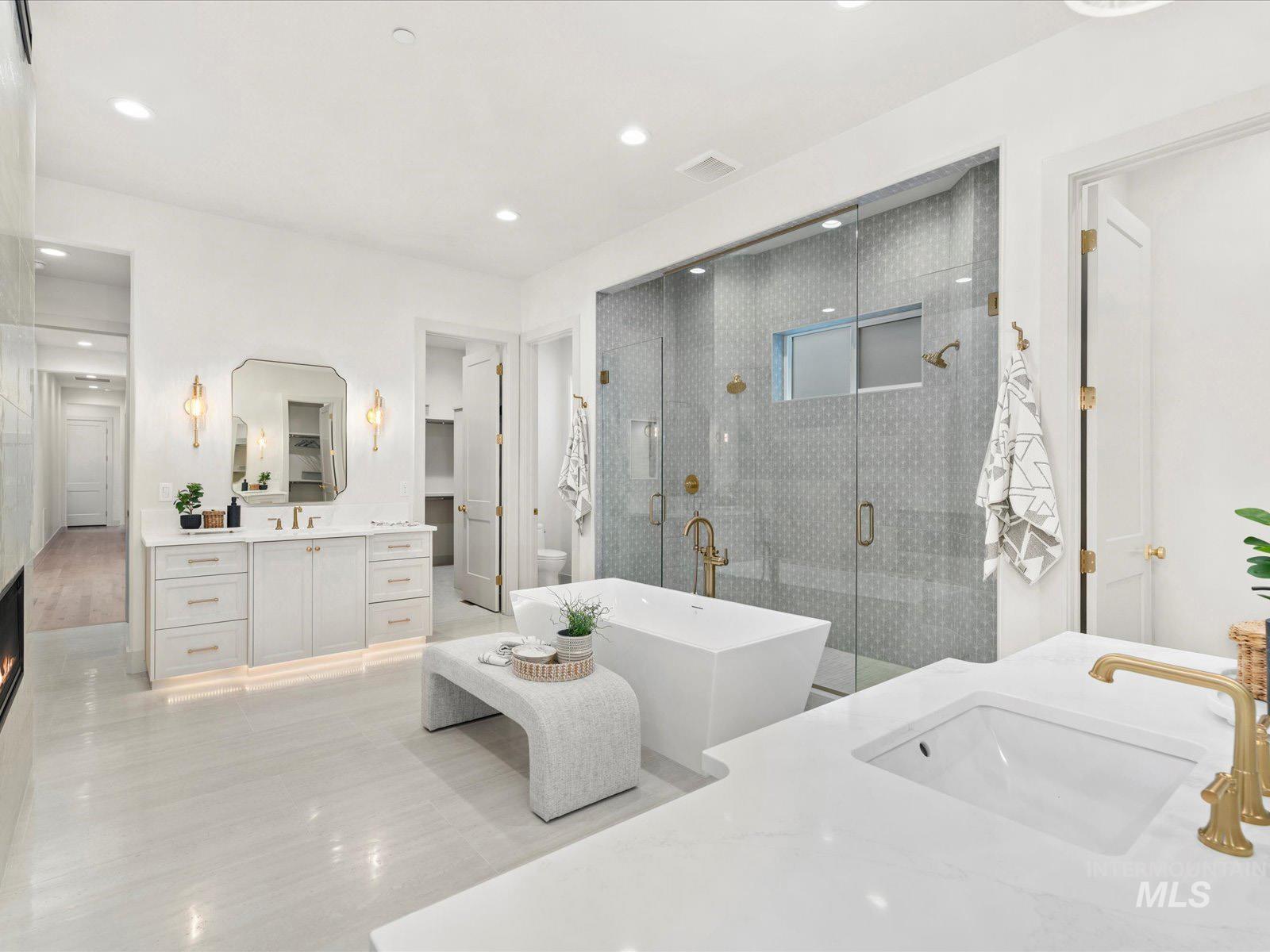 Full bath with two vanities, a stall shower, and a freestanding bath