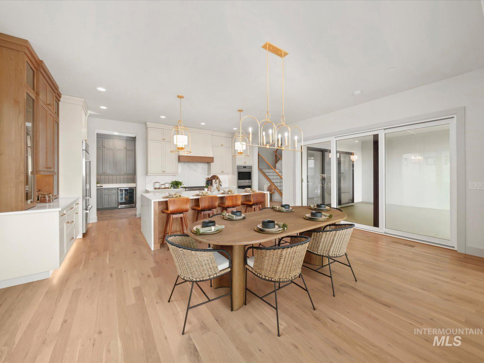 Dining area featuring light wood-style floors, wine cooler, and hanging lights