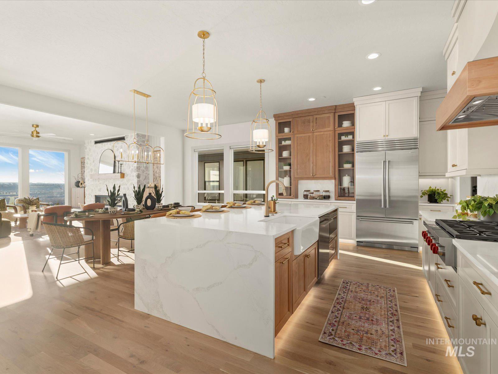 Kitchen with light stone countertops, pendant lighting, stainless steel appliances, light wood-style flooring, and two tone cabinetry