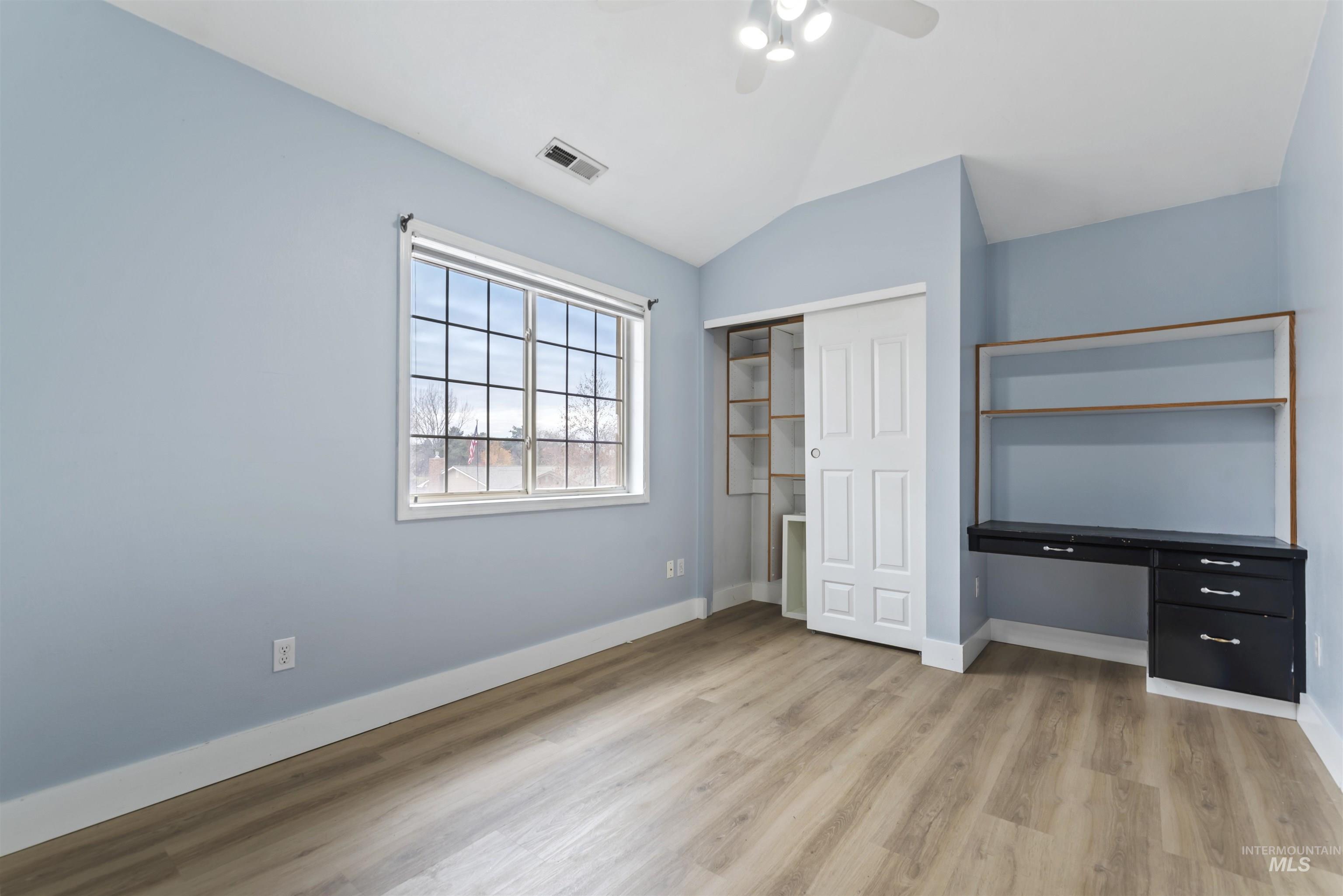 Unfurnished bedroom featuring lofted ceiling, a closet, light wood-type flooring, and ceiling fan