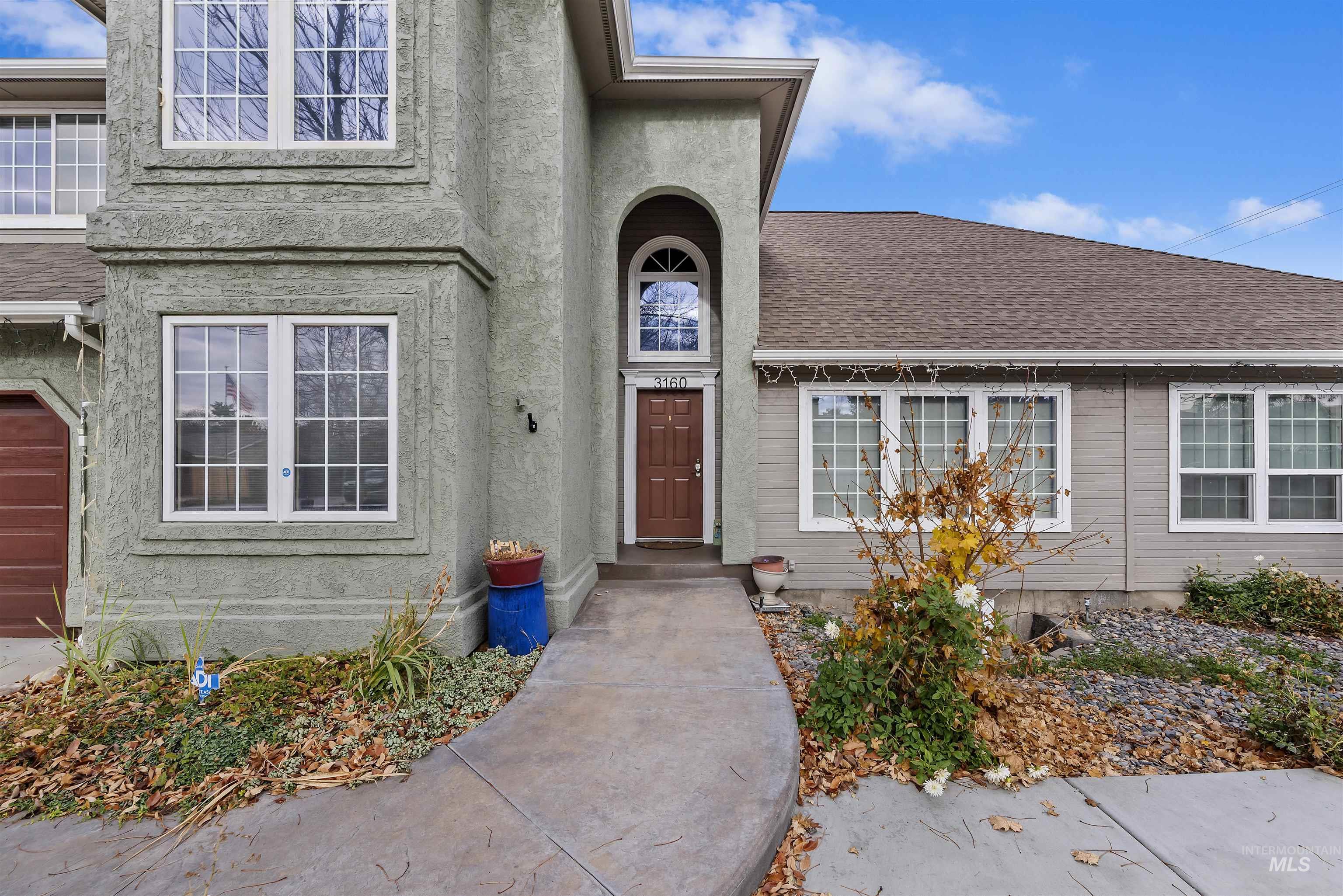View of exterior entry featuring stucco siding and a shingled roof